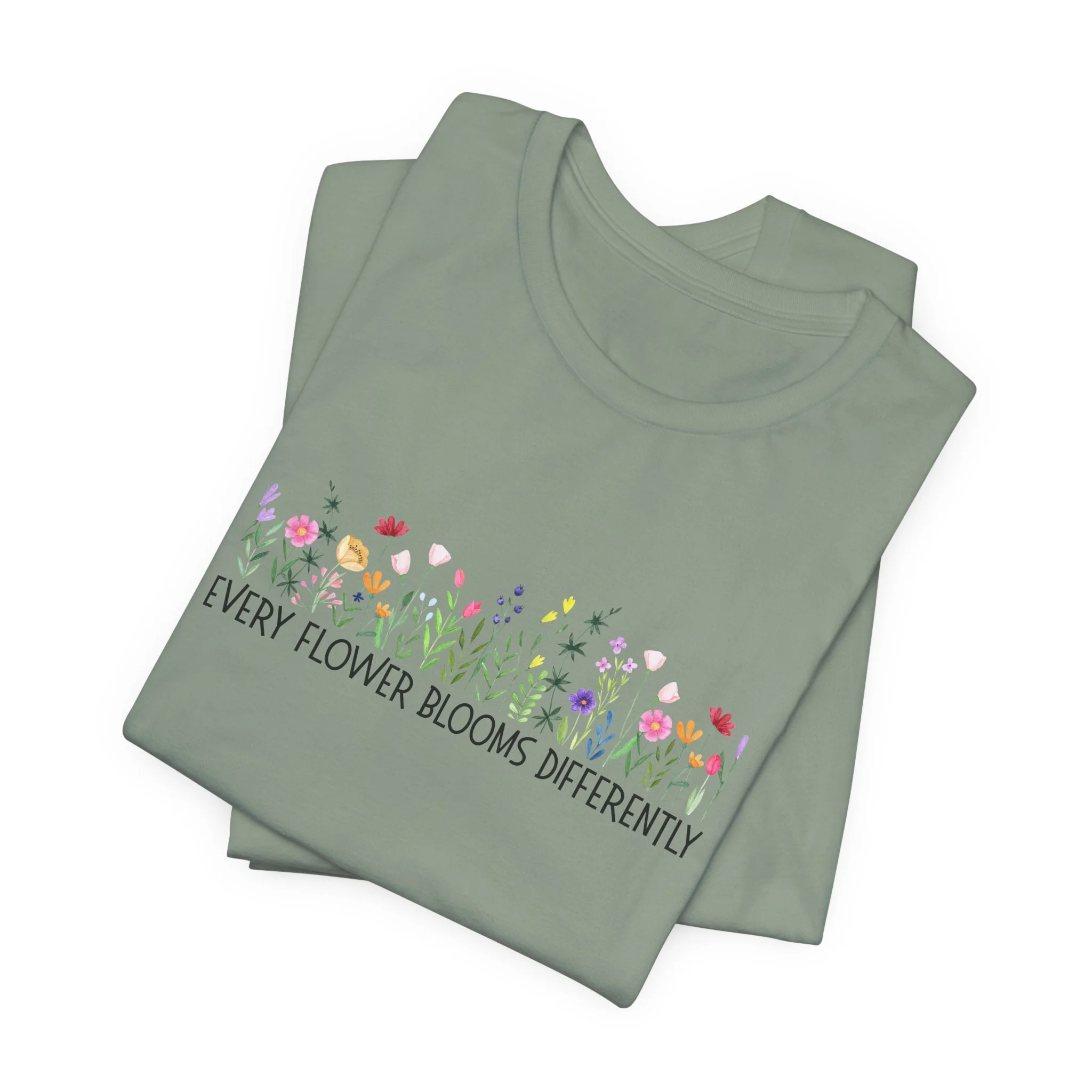 Folded sage green t-shirt featuring Every Flower Blooms Differently graphic