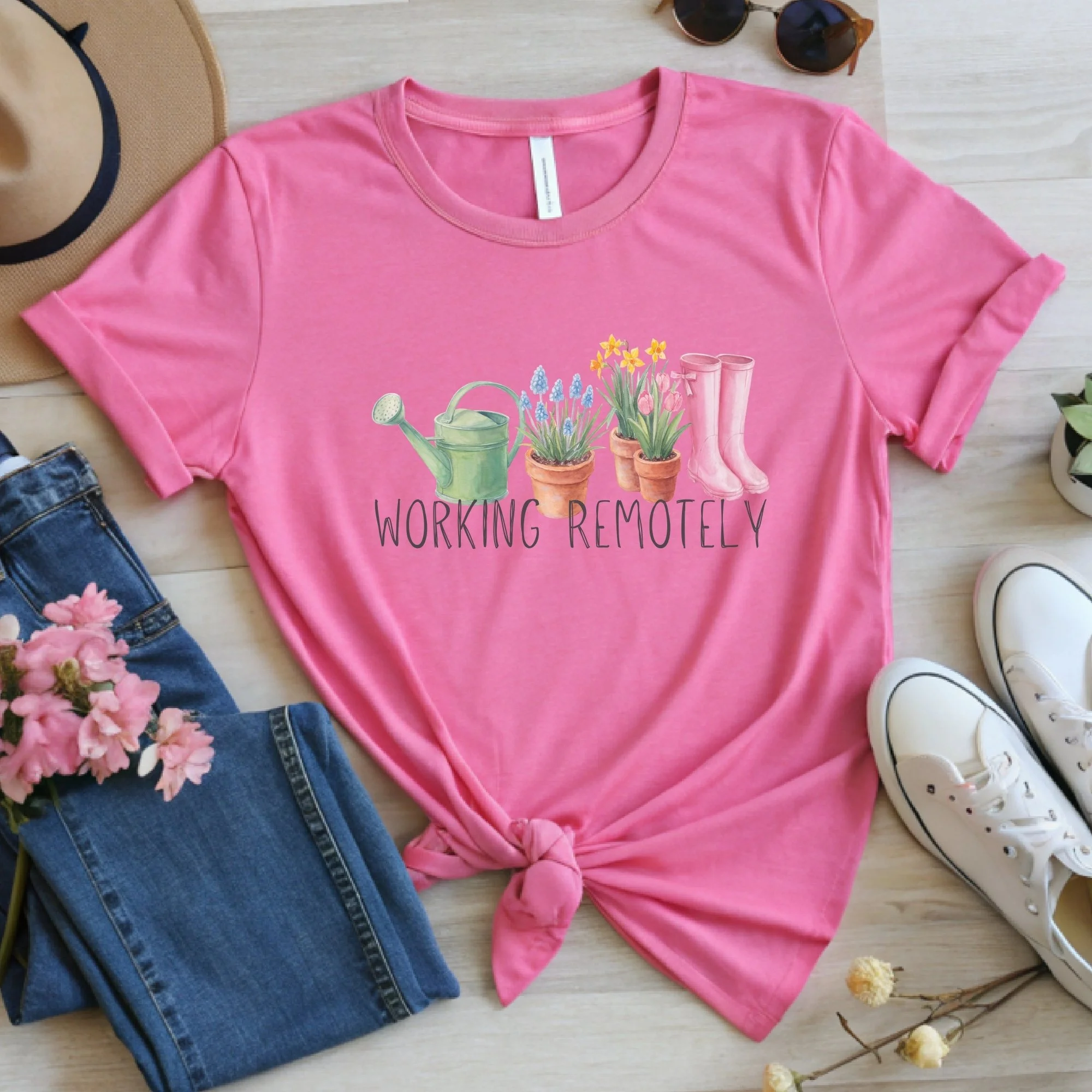 Daytime styled view of Working Remotely graphic shirt on charity pink tee with jeans, sneakers, and spring accessories