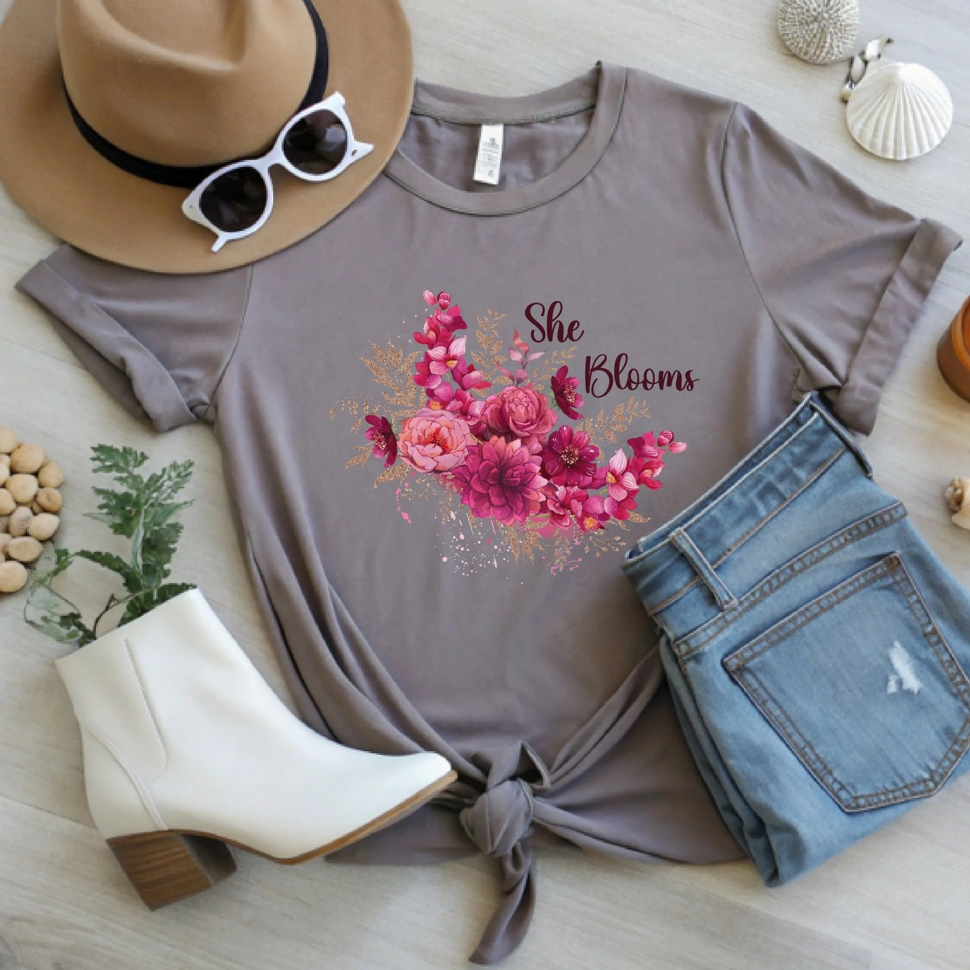Daytime styled view of She Blooms graphic shirt on pebble brown tee with jeans, sneakers, and spring accessories