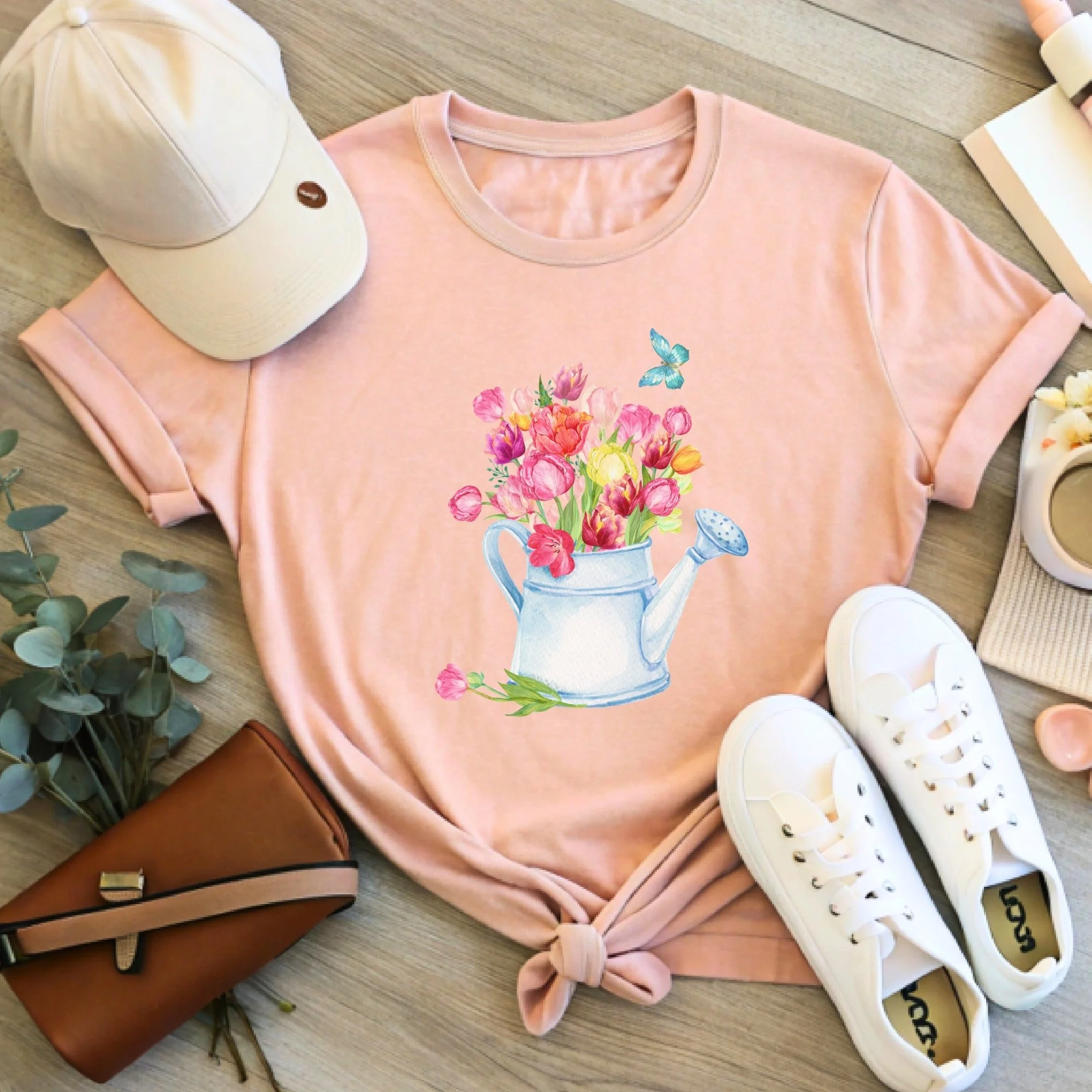 Daytime styled view of Tulips in Watering Can graphic shirt on peach tee with jeans, sneakers, and spring accessories
