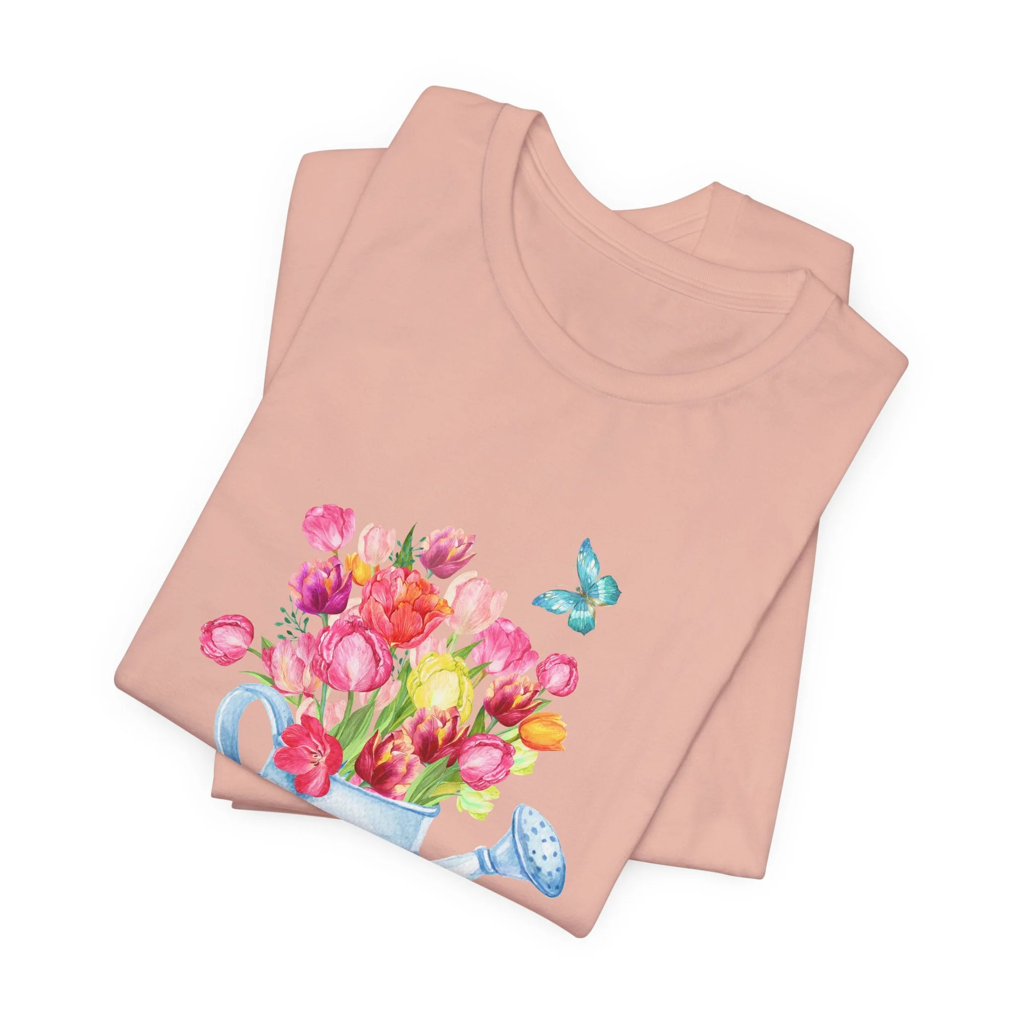 Folded peach t-shirt featuring Tulips in Watering Can graphic