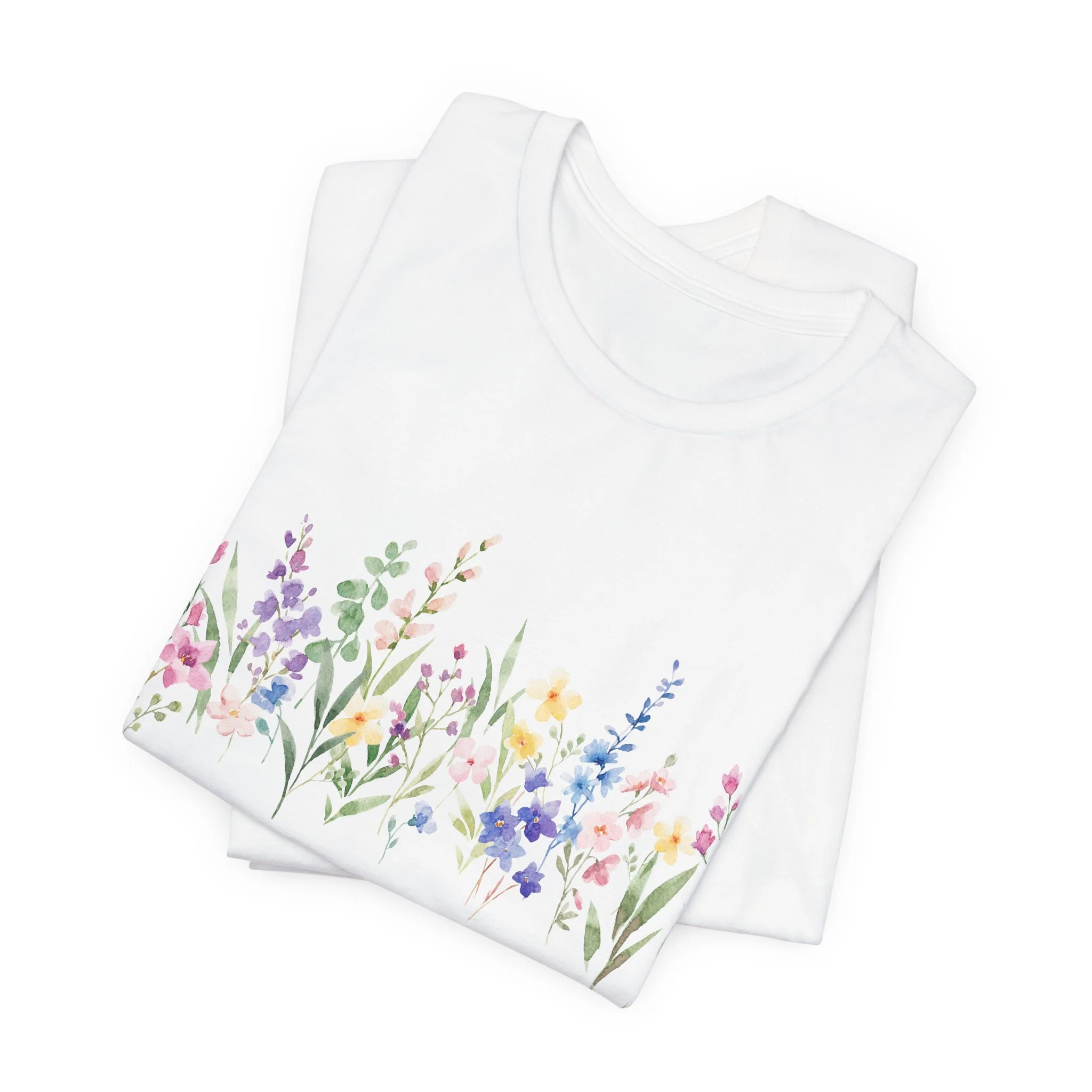 Folded white t-shirt with pastel watercolor wildflower border illustration across the bottom