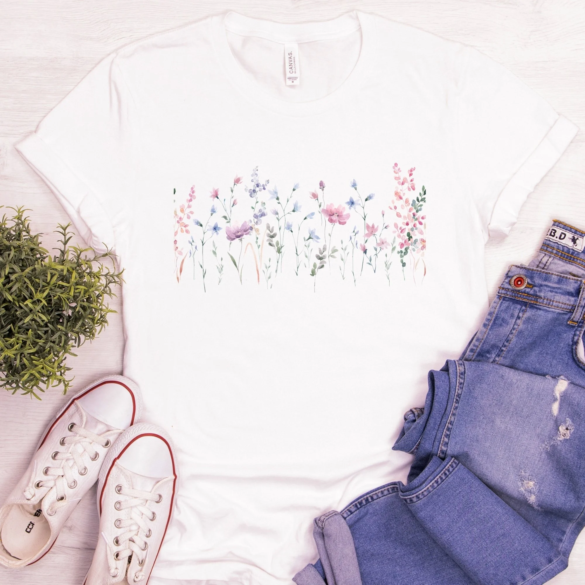 Watercolor wildflower border shirt on white tee styled with jeans, sneakers, and spring accessories
