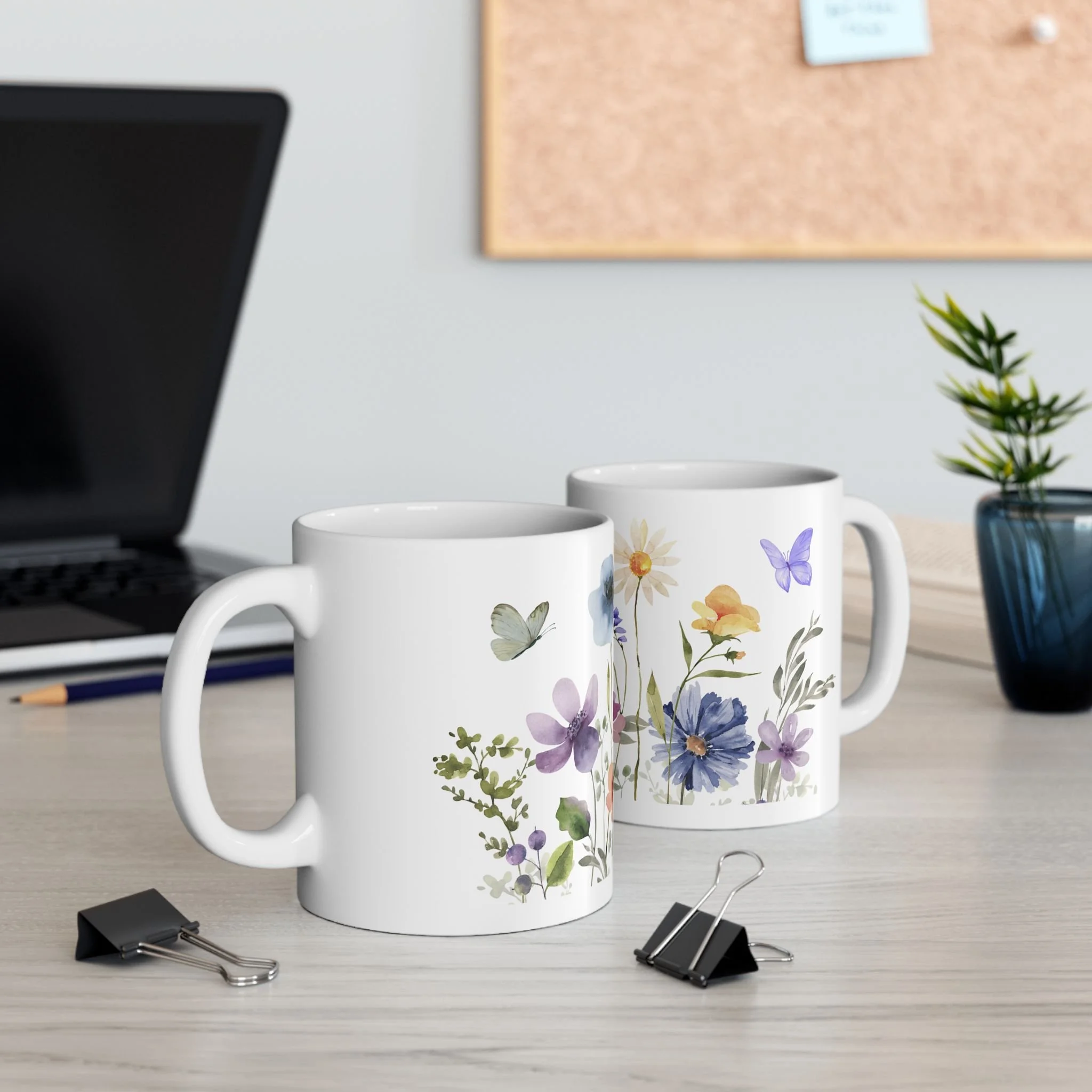 Styled desk scene with two wildflower garden mugs featuring soft floral and butterfly designs