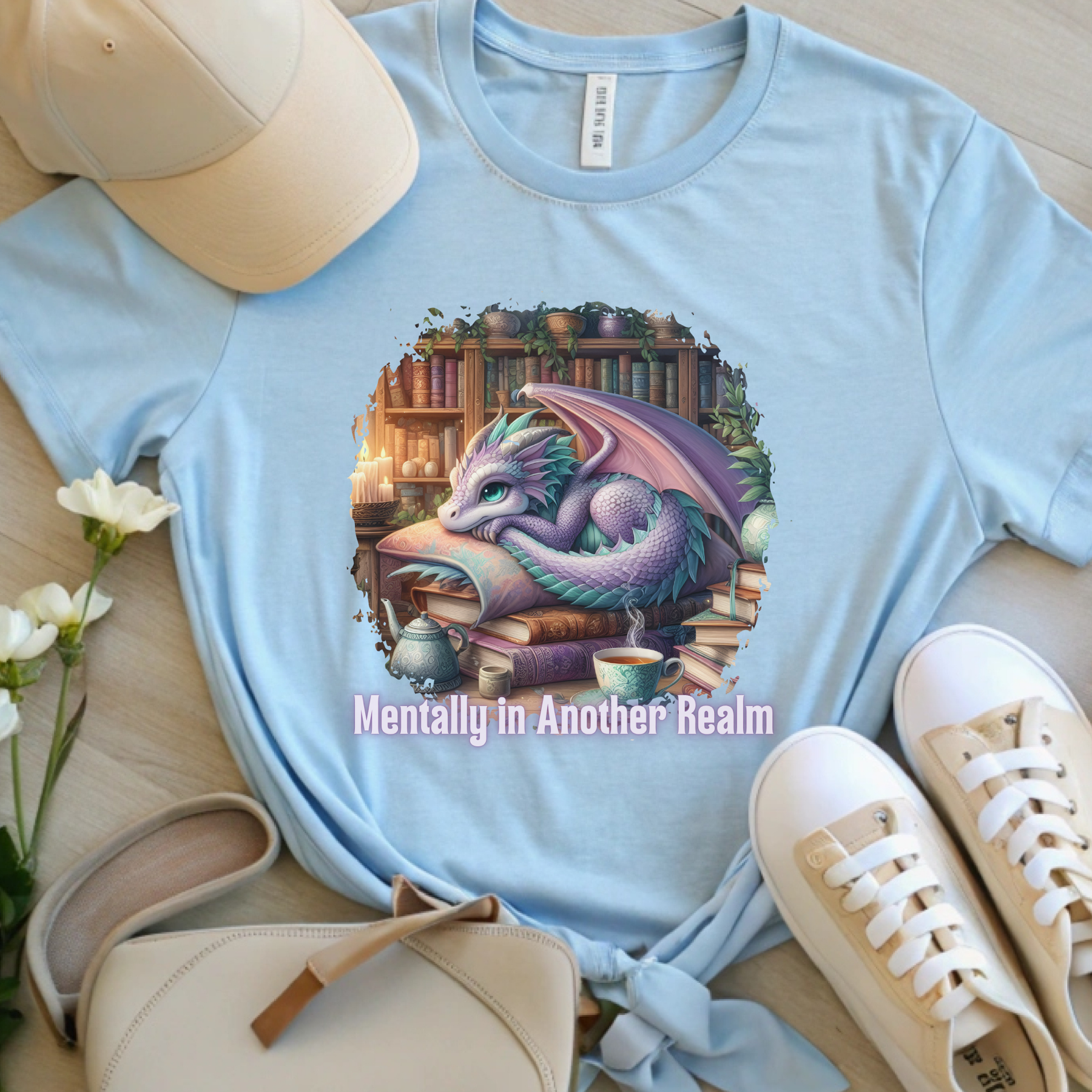 Light blue fantasy reader t-shirt featuring a sleeping purple dragon and the phrase "Mentally in Another Realm."