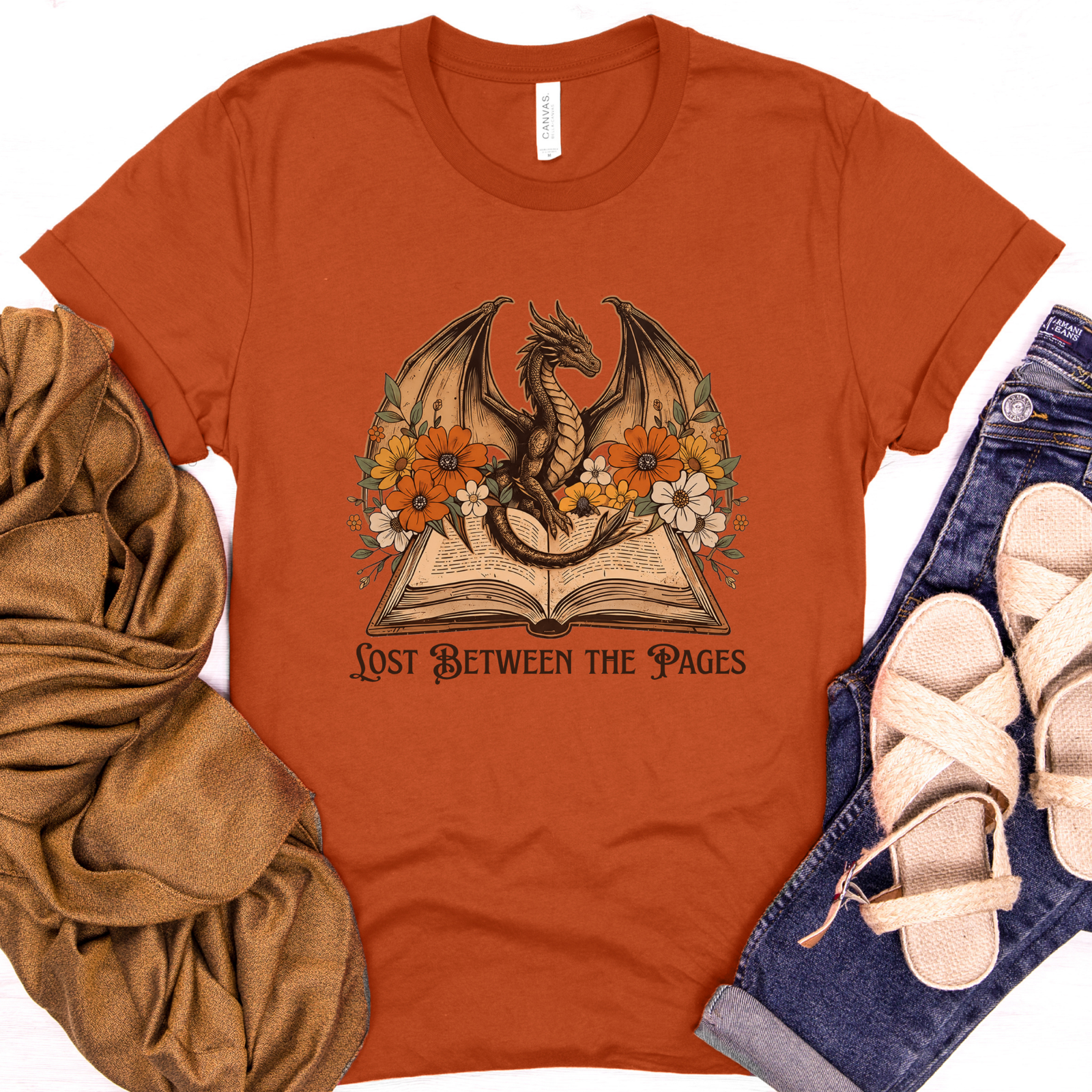 Autumn (rust) fantasy reader t-shirt featuring a dragon, open book, and fall flowers with "Lost Between the Pages" text.