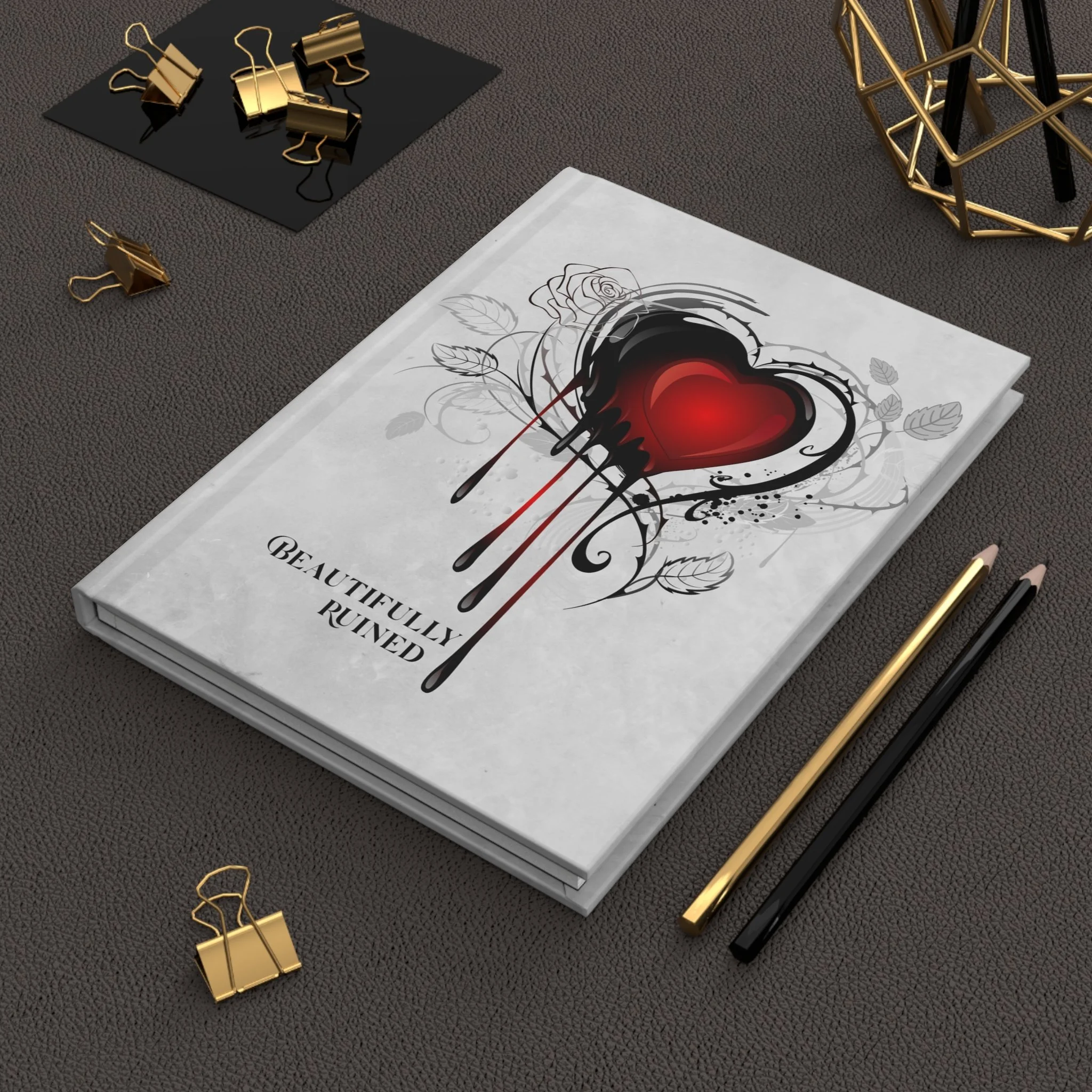 Beautifully Ruined hardcover journal with front cover artwork on desk with pens