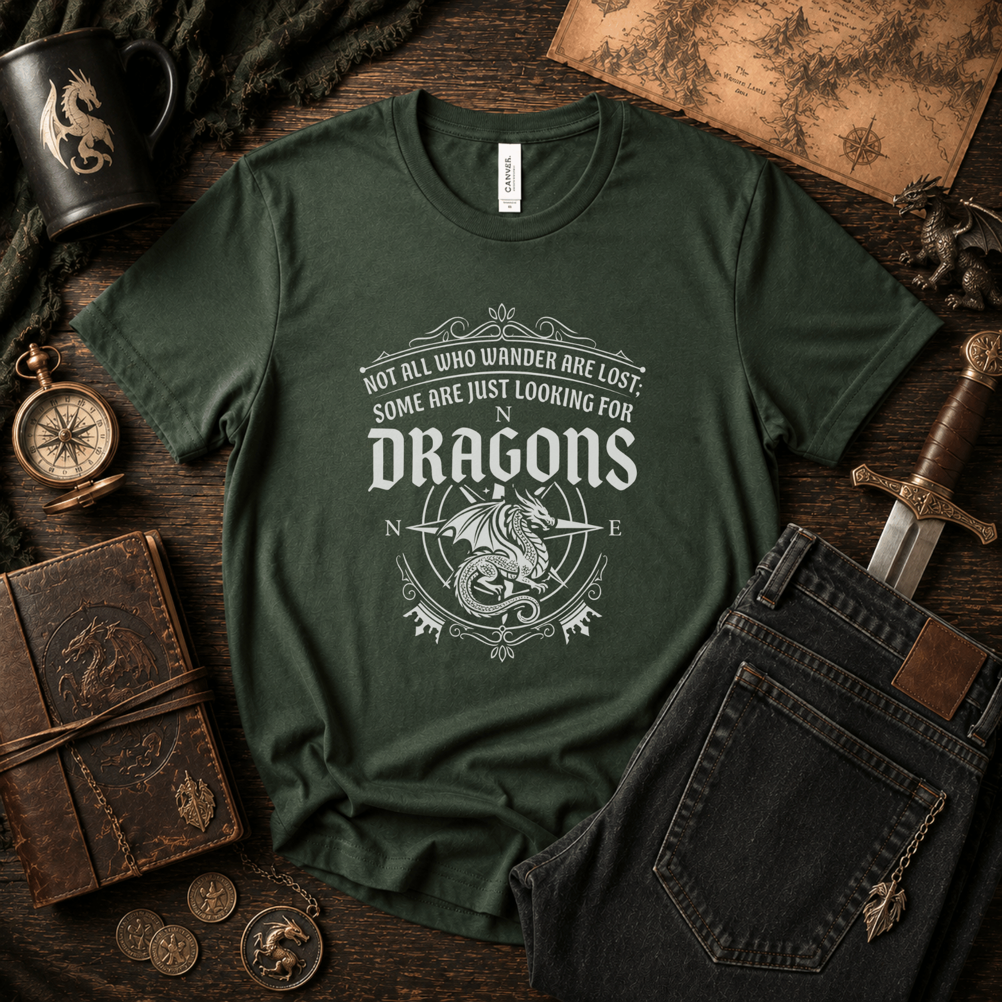Lifestyle mockup of a Forest Green Bella+Canvas fantasy dragon graphic t-shirt styled with vintage books and fantasy-inspired accessories.