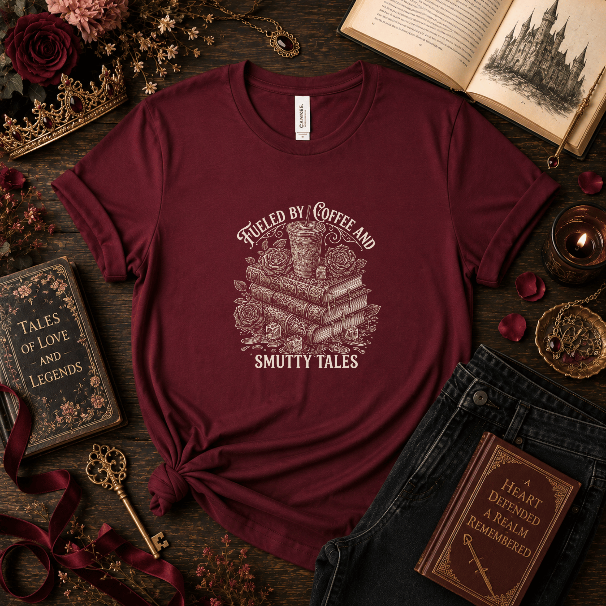 Lifestyle mockup of a Maroon Bella+Canvas fantasy reader t-shirt styled with antique books, coffee, roses, and dark academia accessories.