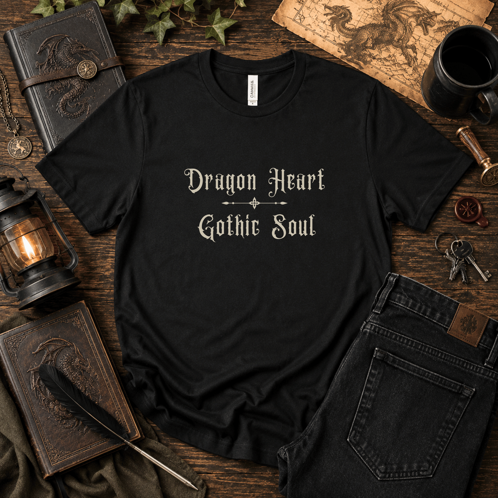 Lifestyle mockup of a Black Bella+Canvas "Dragon Heart, Gothic Soul" t-shirt styled with antique books, maps, lanterns, and dark academia-inspired accessories.