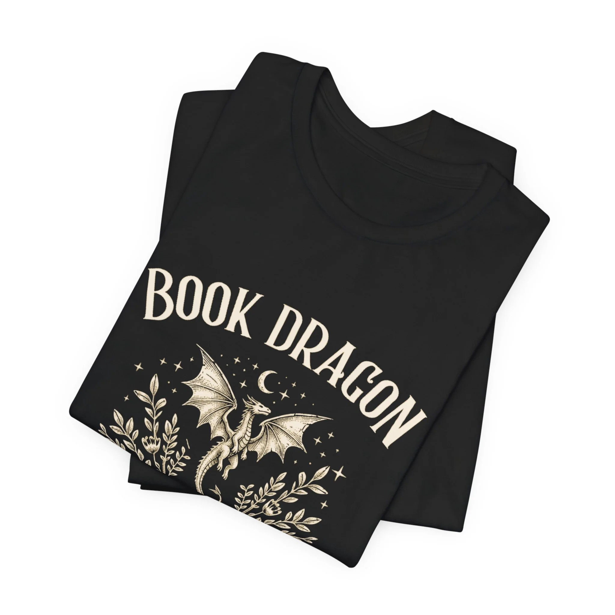 Folded Black Bella+Canvas t-shirt with a whimsical book dragon illustration.