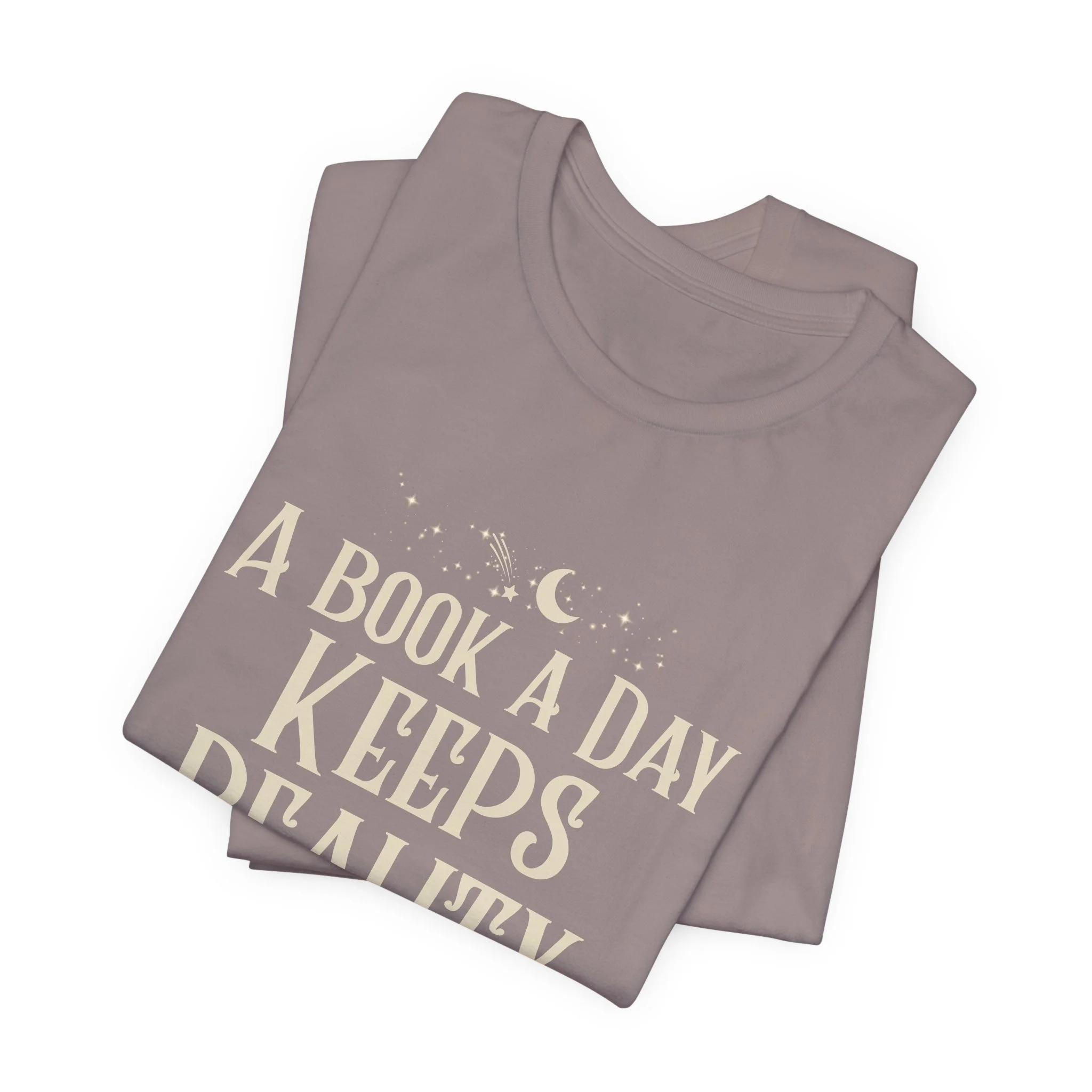 Folded Pebble Brown Bella+Canvas t-shirt featuring the "A Book a Day Keeps Reality Away" design.