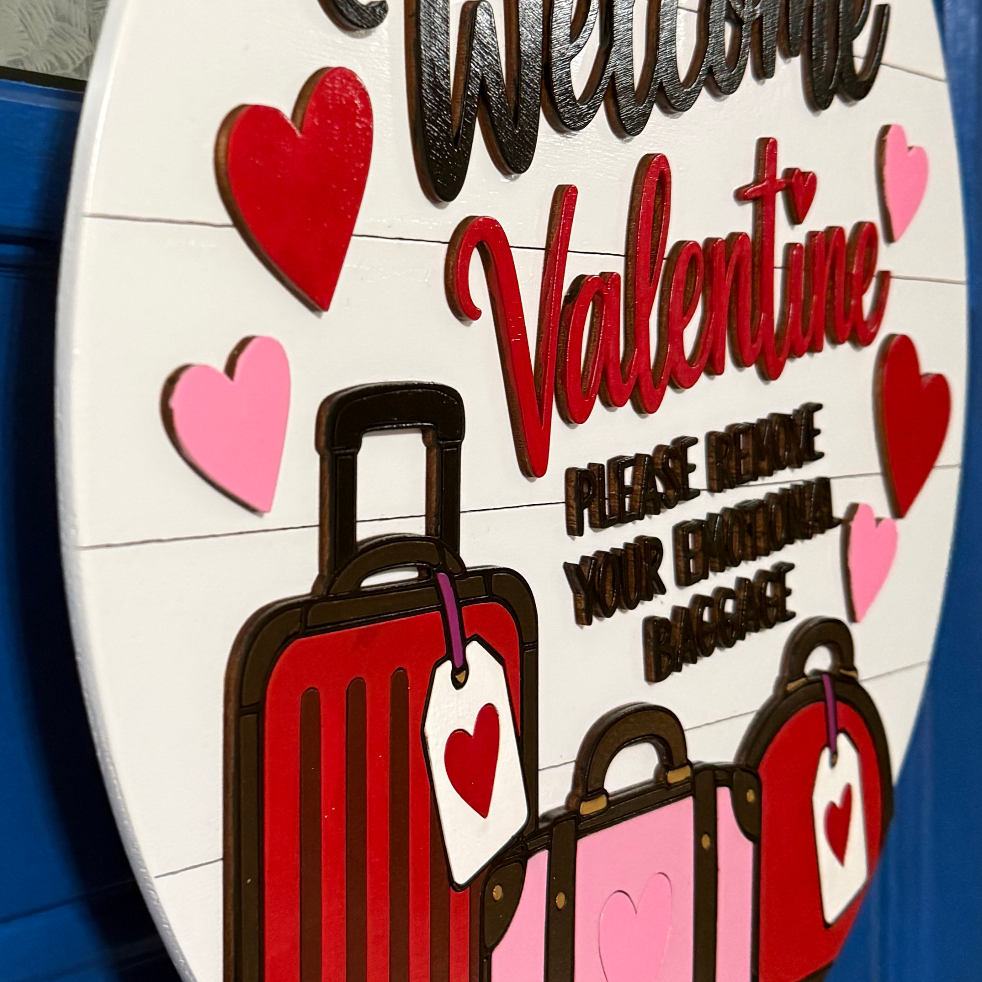 Close-up of pink and red hearts, emotional baggage wording, and layered suitcase details
