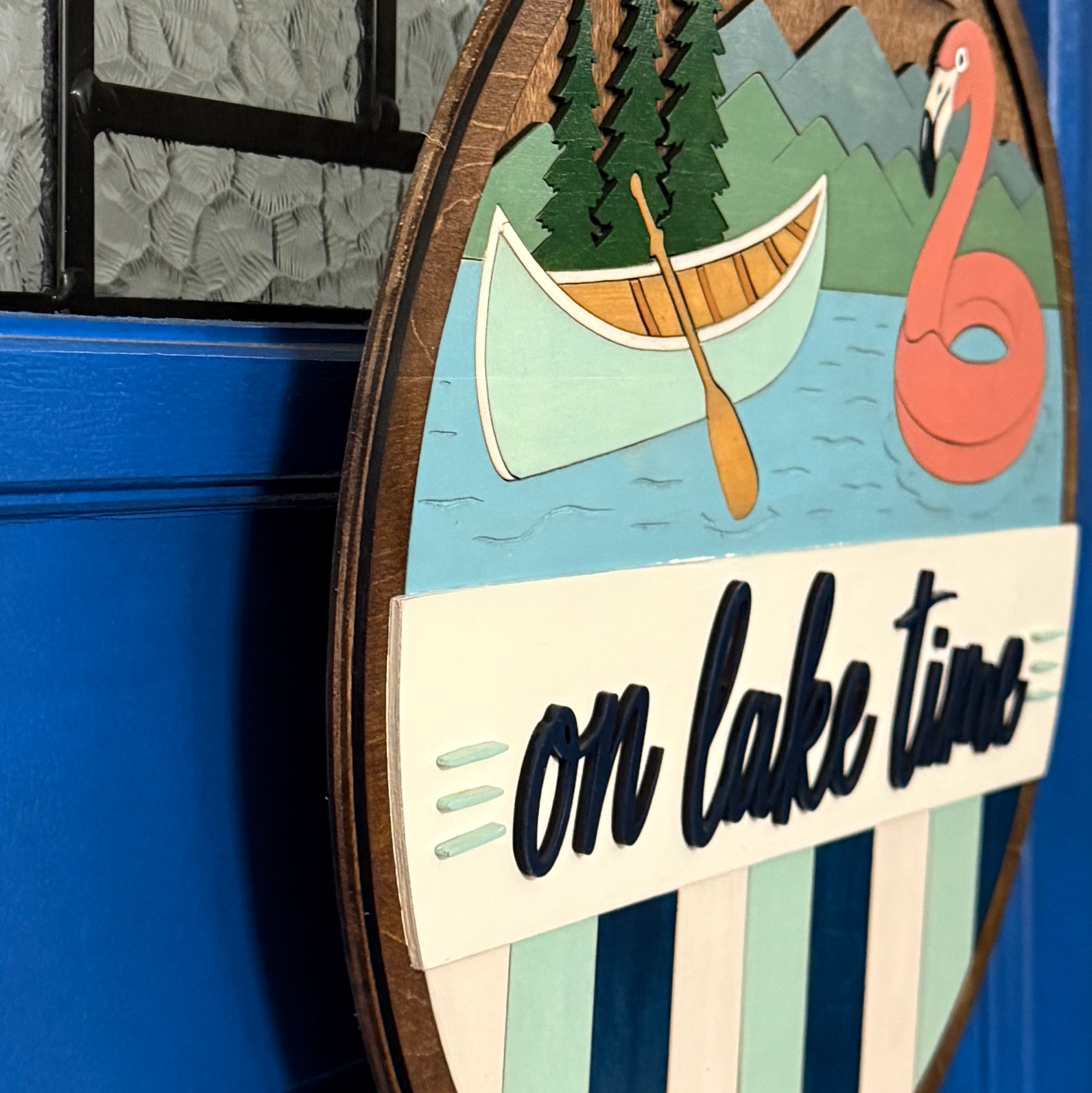 Side profile showing the layered wood construction and dimensional elements of the On Lake Time door hanger.
