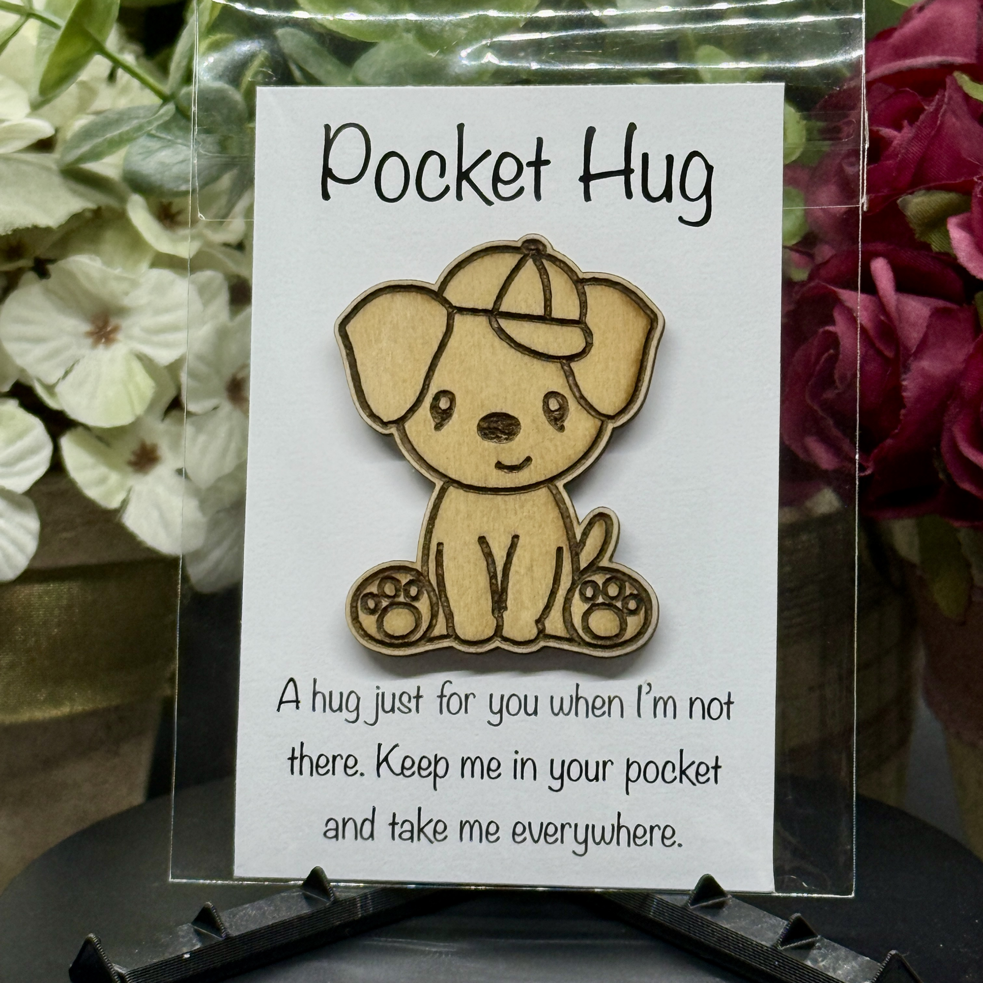 Cap Pup Pocket Hug token on printed card with white and pink floral background – wooden puppy wearing a cap