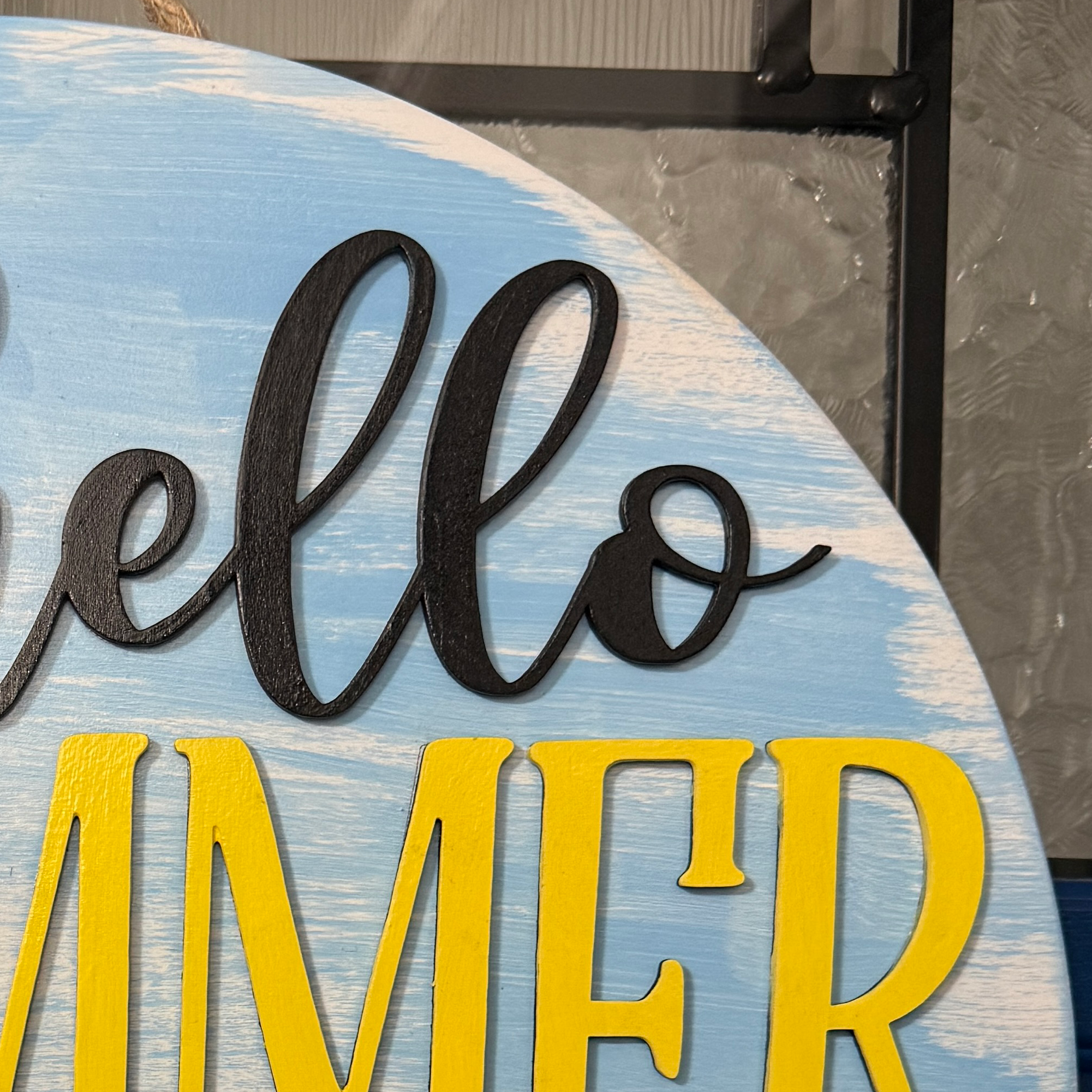 Close-up of black hello script and yellow summer lettering on rustic blue wood surface