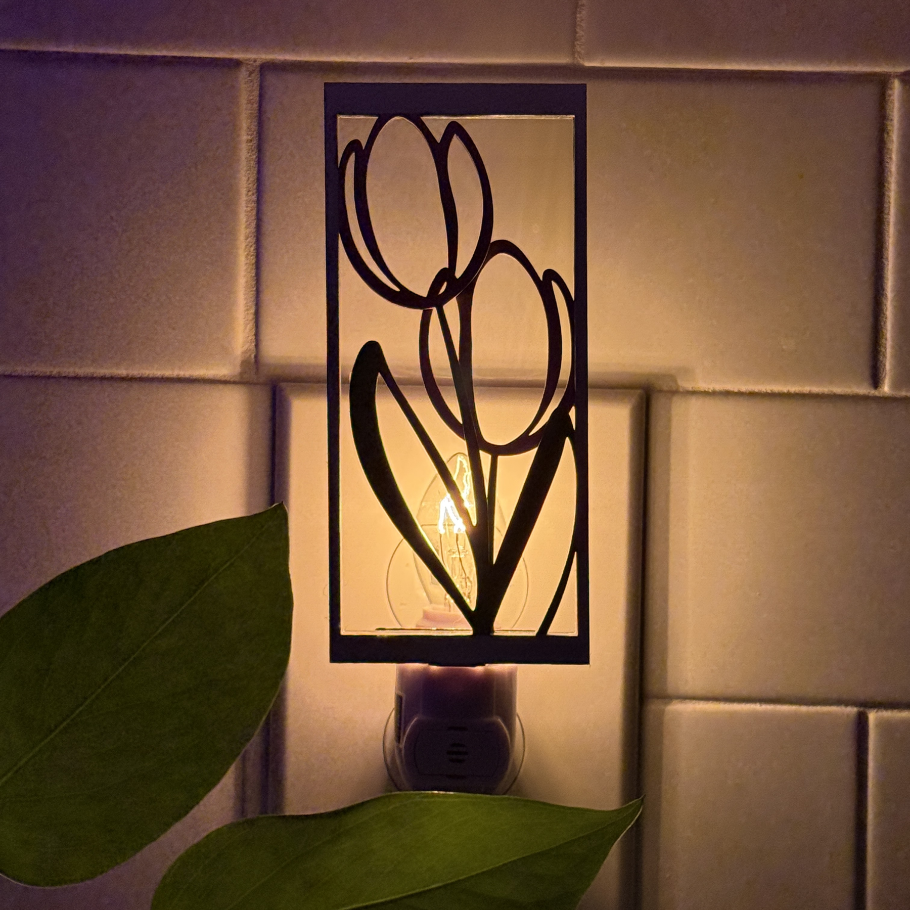 Backlit tulip night light glowing warmly in a dark kitchen setting with flower outlines softly illuminated