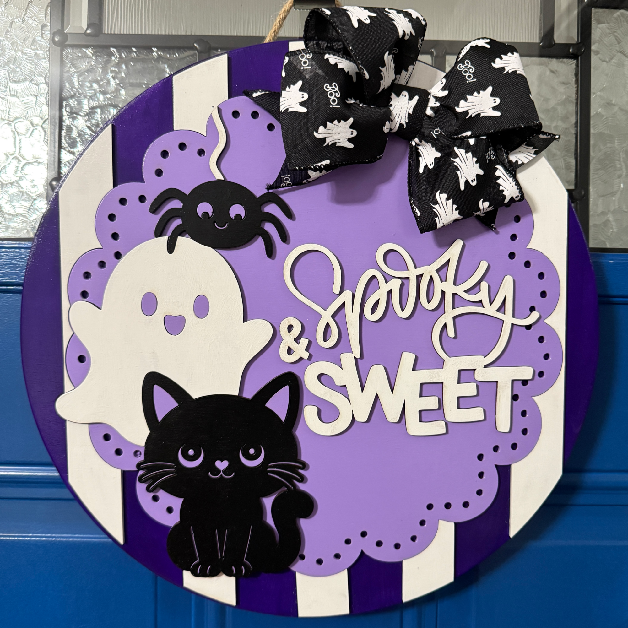 Spooky and Sweet Halloween round wood door hanger with purple stripes, layered ghosts, black cat, spider, and black Halloween bow