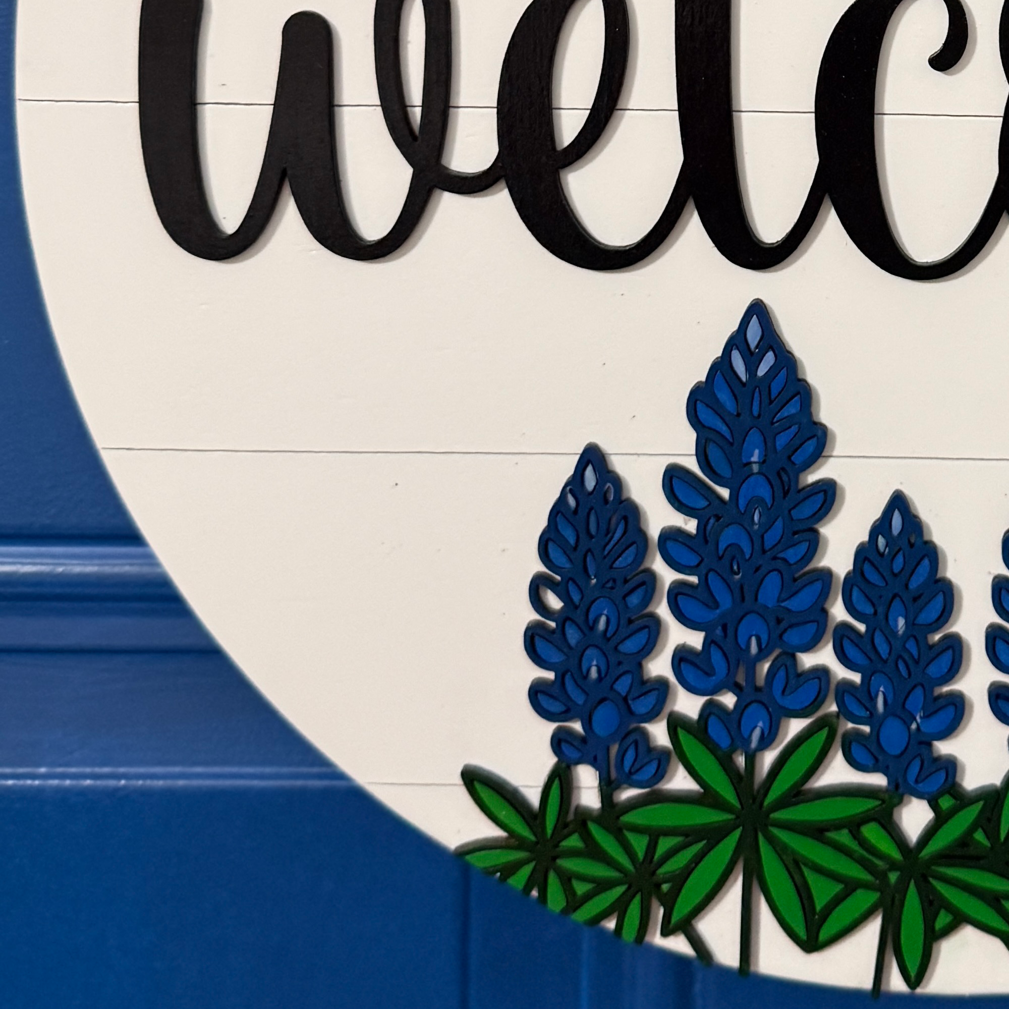 Layered bluebonnet floral detail on round wood door hanger
