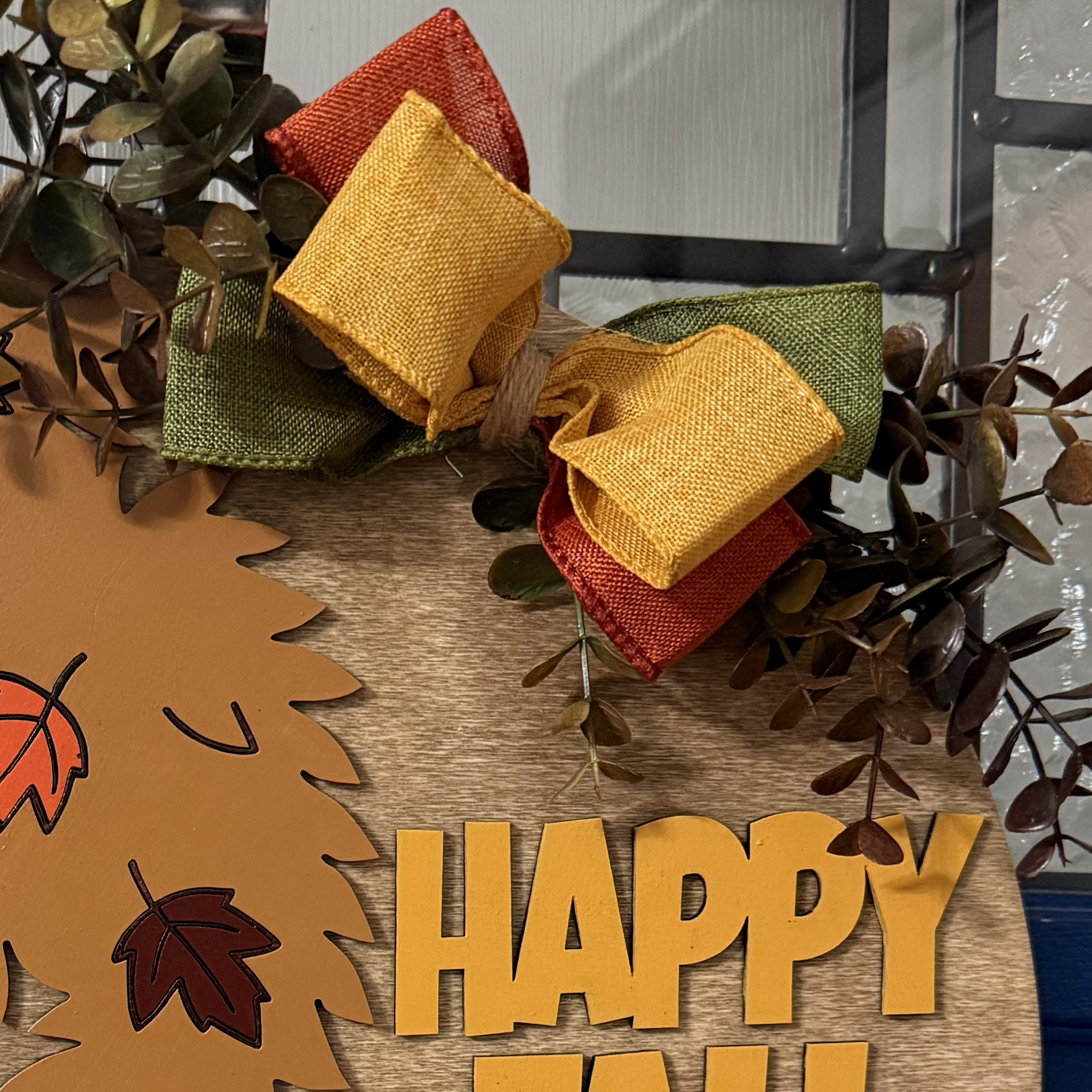 Close-up of fall door hanger highlighting painted leaves, bow details, and character accents