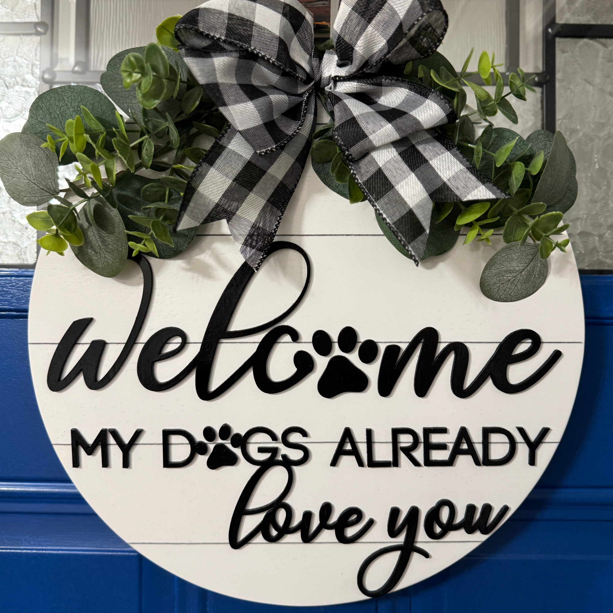 Full view of round white welcome sign with paw print detail and “my dogs already loves you” message