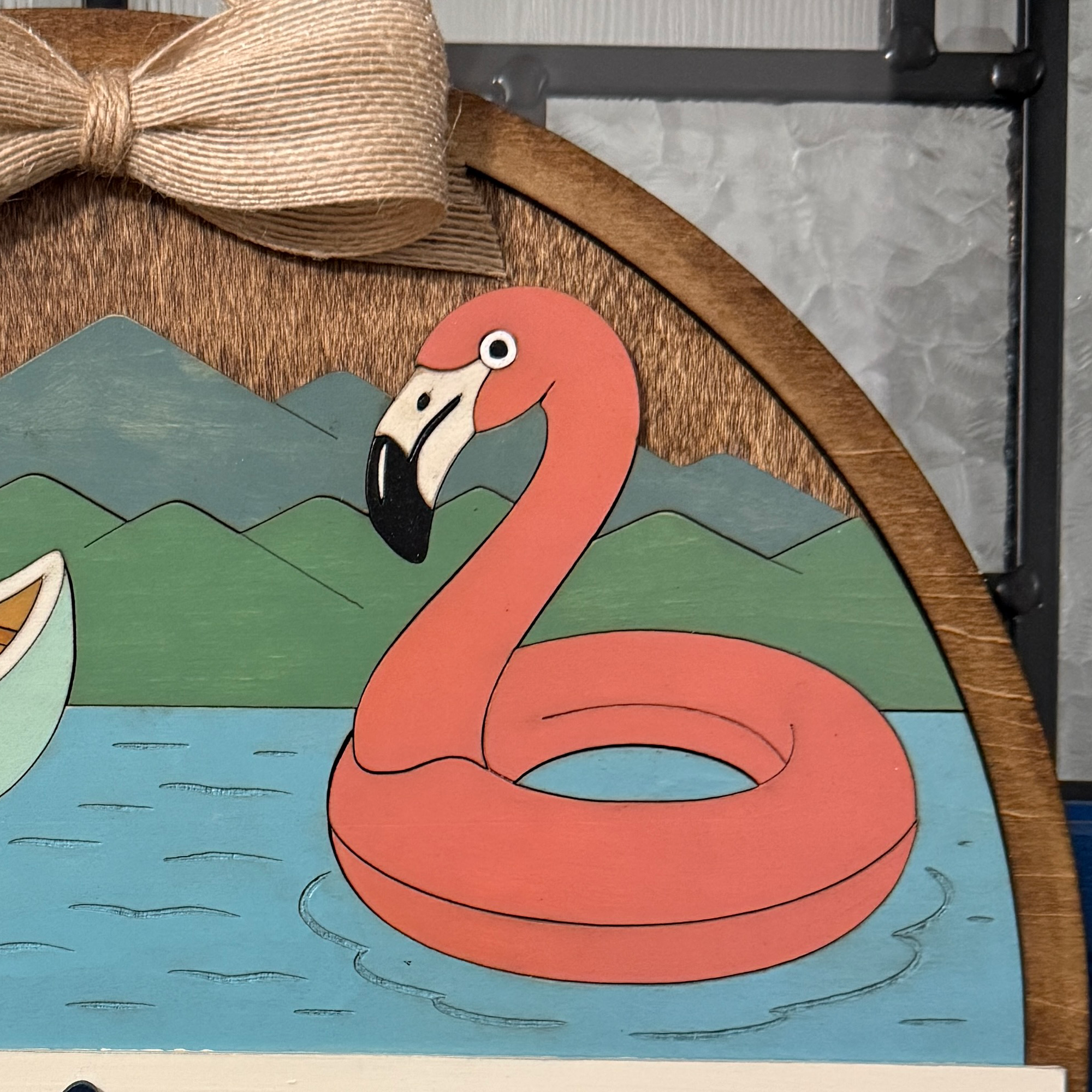 Close-up of flamingo float and mountain details beneath the natural linen bow.