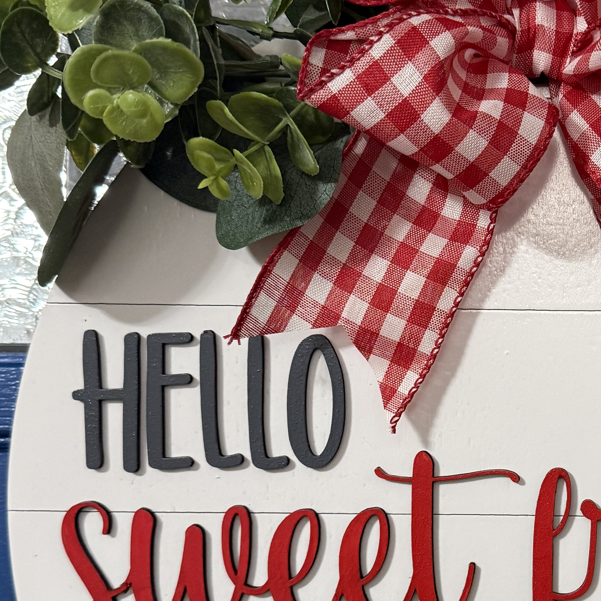 Close-up of charcoal “HELLO” and raised red “Sweet Friends” script on white shiplap-style background