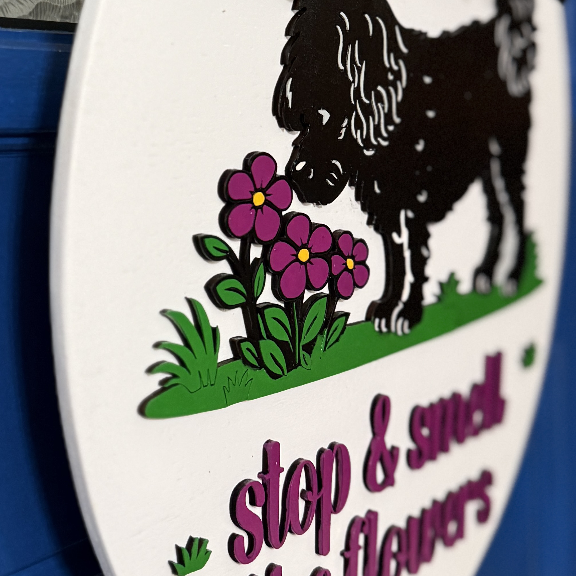 Side angle view of black dog silhouette and pink flowers with layered wood construction on round spring door decor