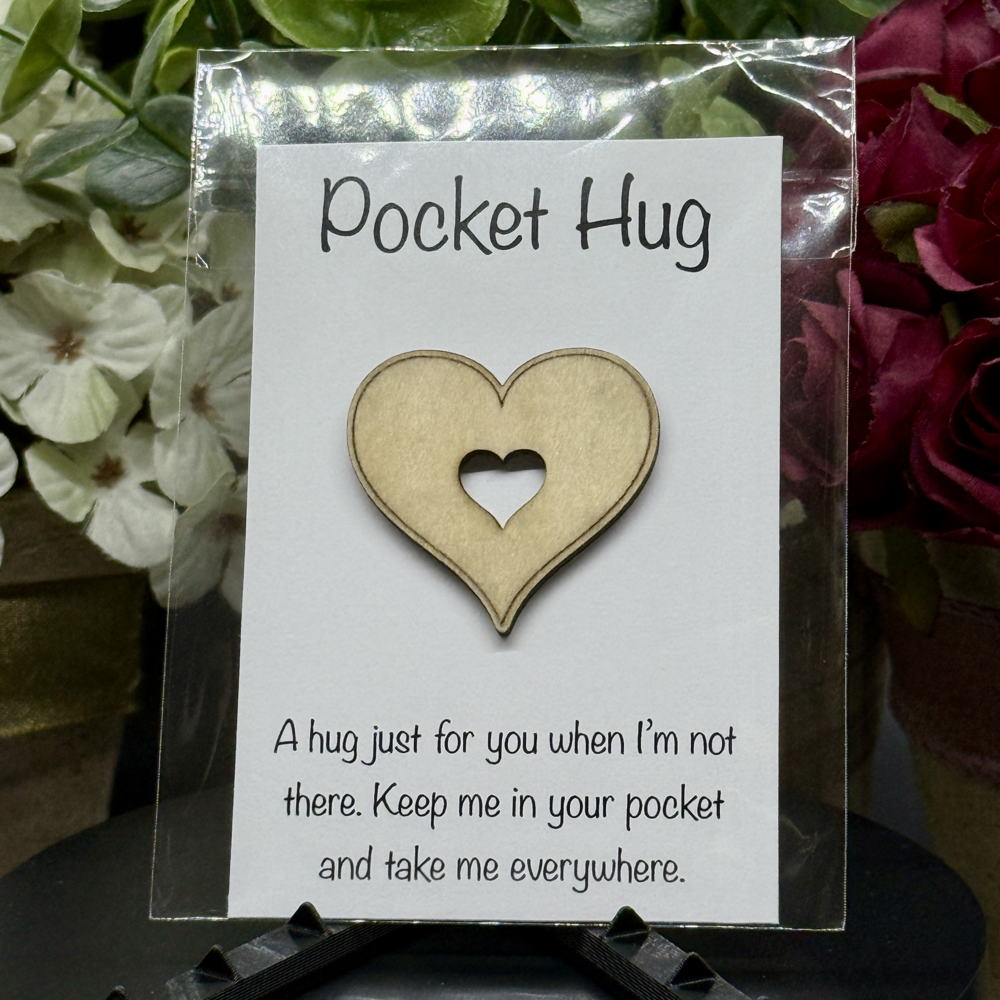 Heart-shaped Pocket Hug token on printed message card with floral background – laser-cut wooden heart with center cutout