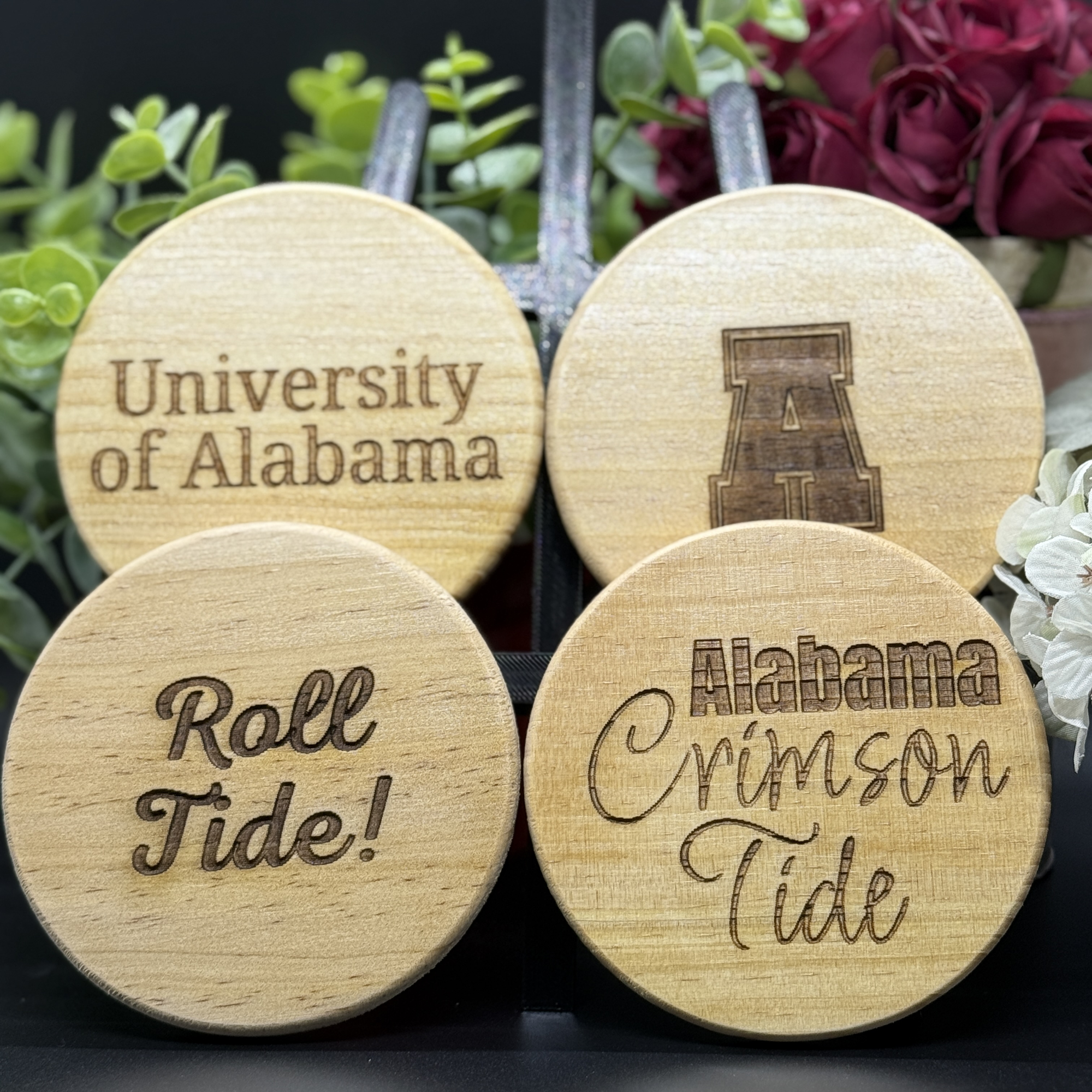 Set of four round Alabama Crimson Tide engraved wooden coasters with unique designs including University of Alabama, Roll Tide, Crimson Tide, and block A logo