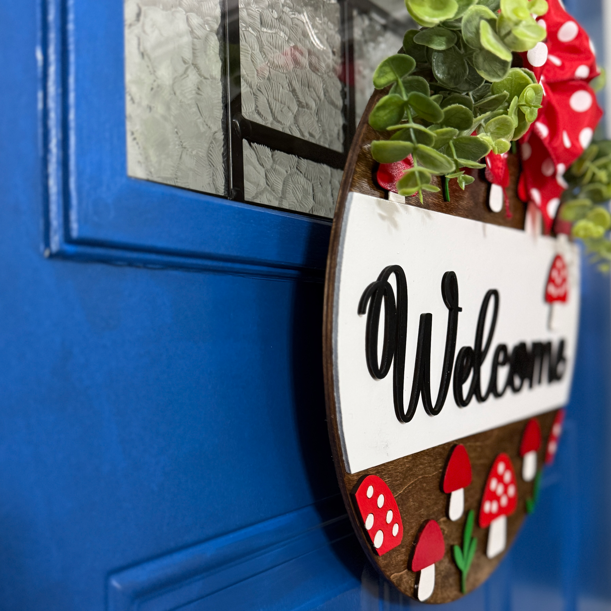 Hand-painted mushroom welcome sign with rustic wood base displayed on blue front door