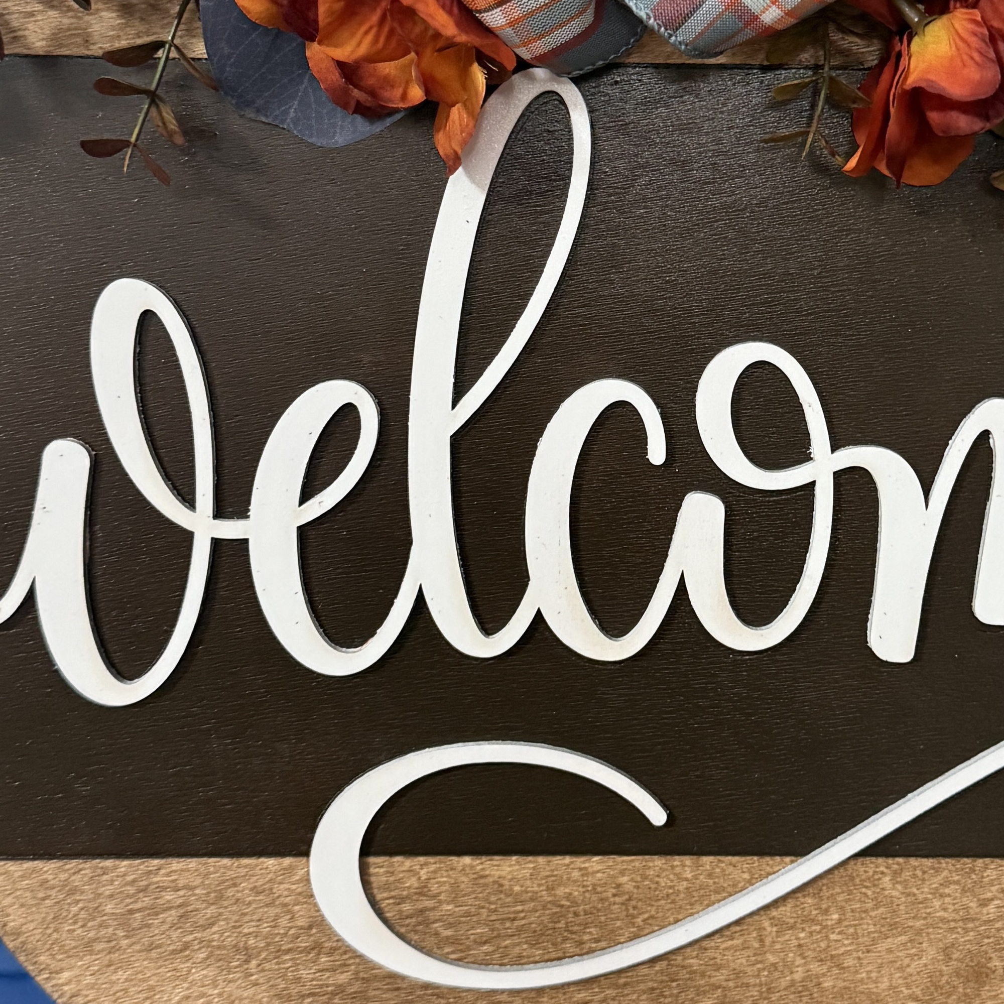 Close-up of “welcome” lettering and layered floral accents on autumn door hanger