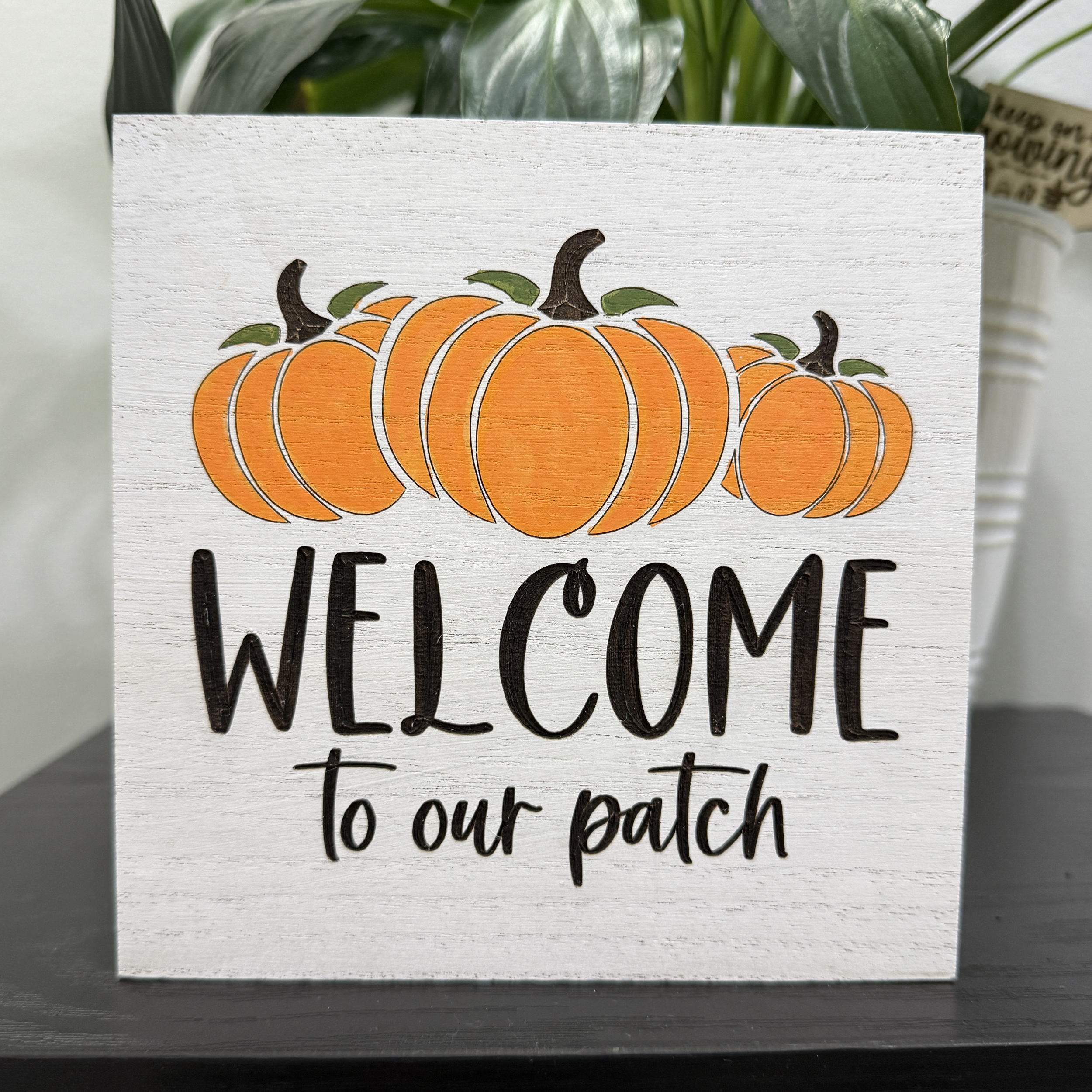 Front view of fall pumpkin shelf sitter with orange pumpkins and “Welcome to our patch” text on whitewashed MDF block