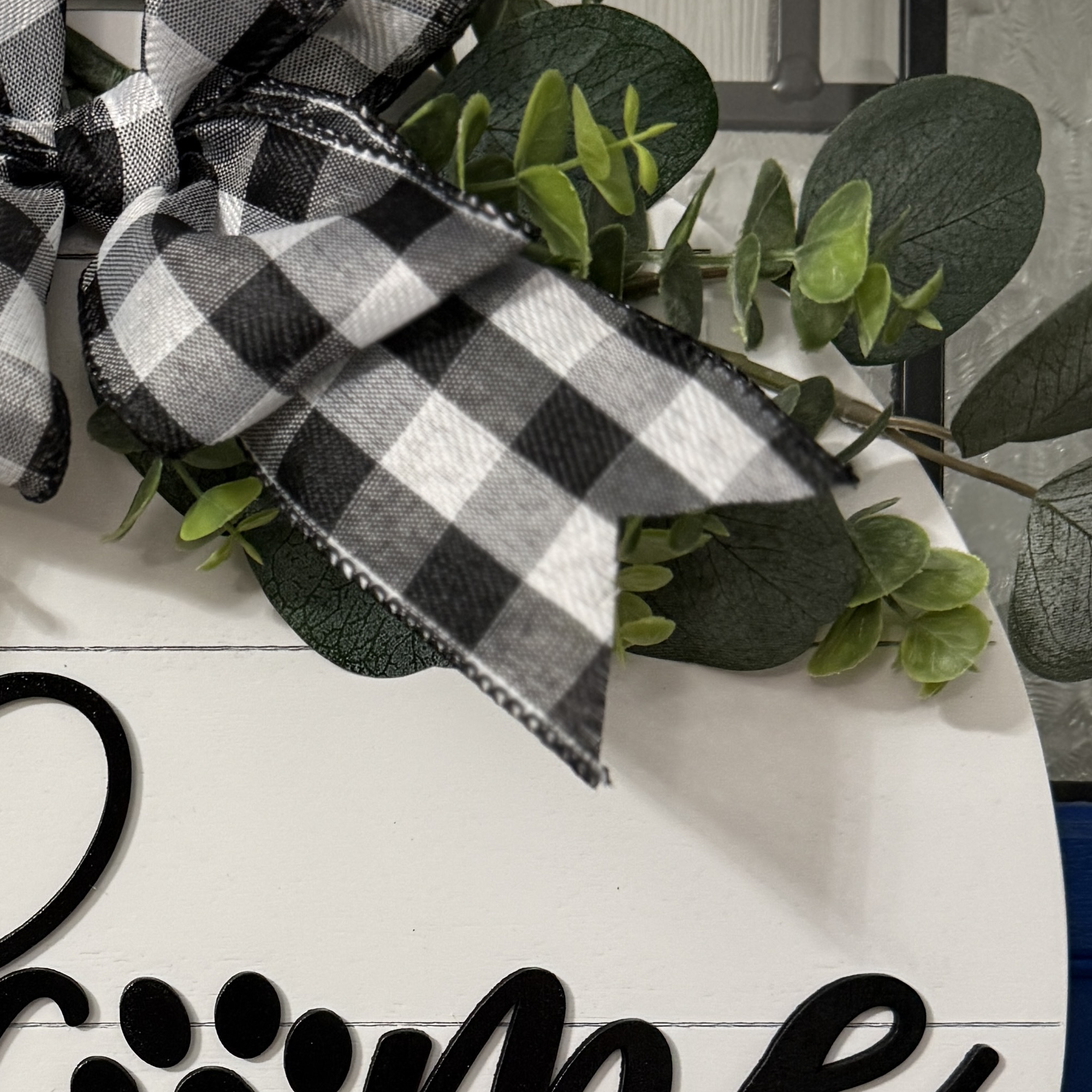 Close-up of greenery and bow detail with black and white ribbon loops