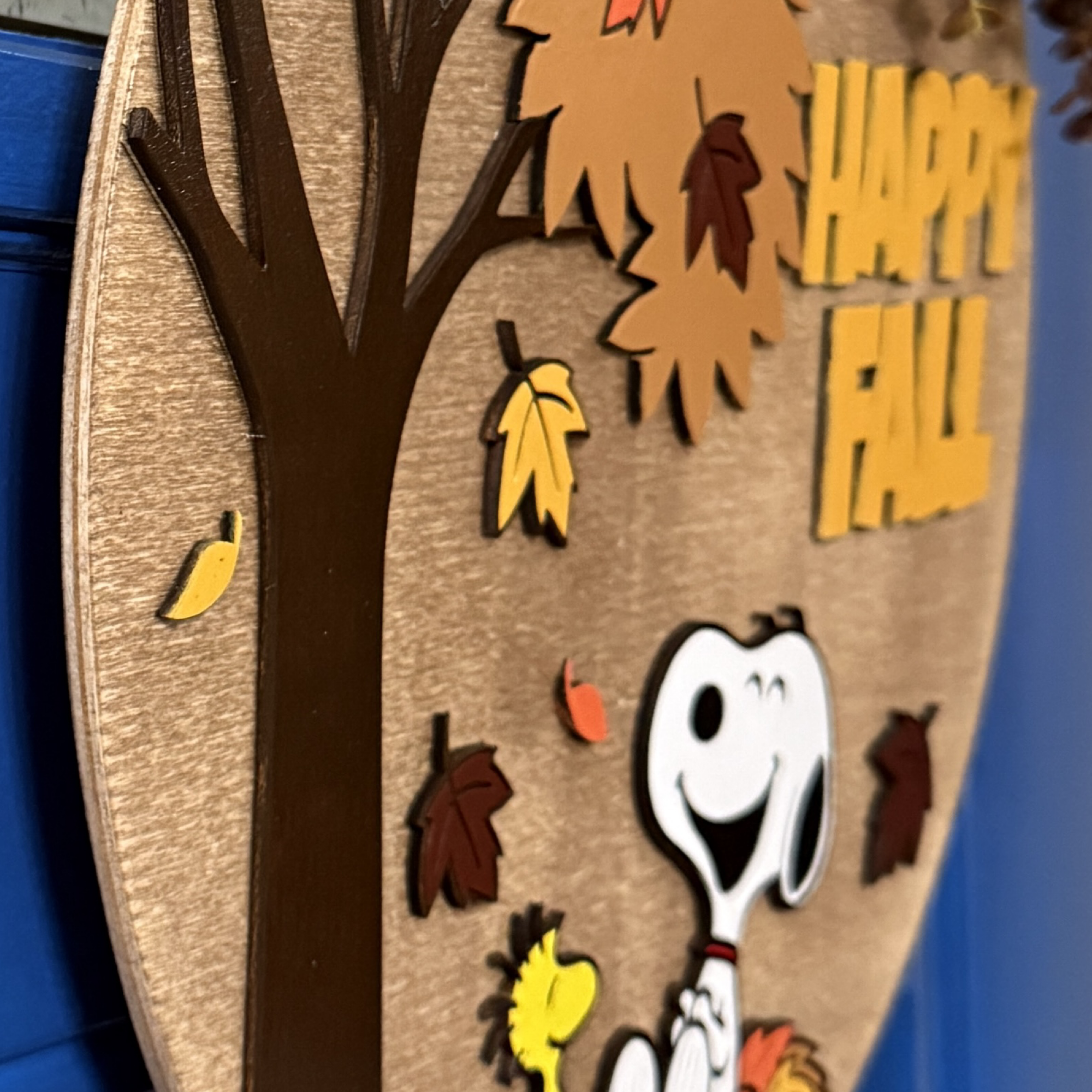 Close-up of fall door hanger highlighting painted leaves, bow details, and character accents