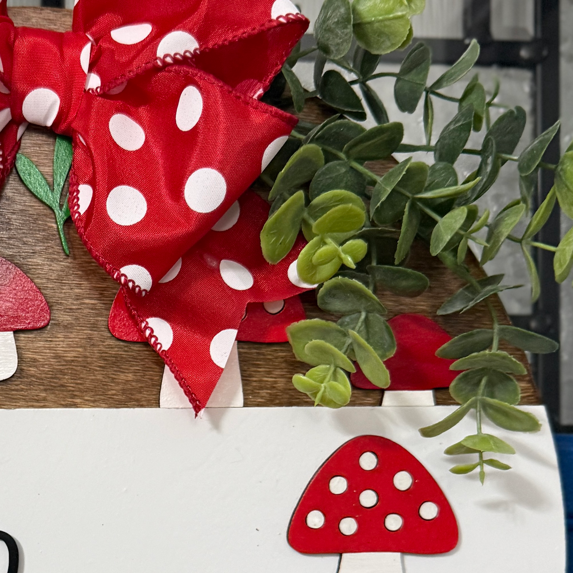 Close-up of red polka dot bow and eucalyptus greenery on mushroom door hanger