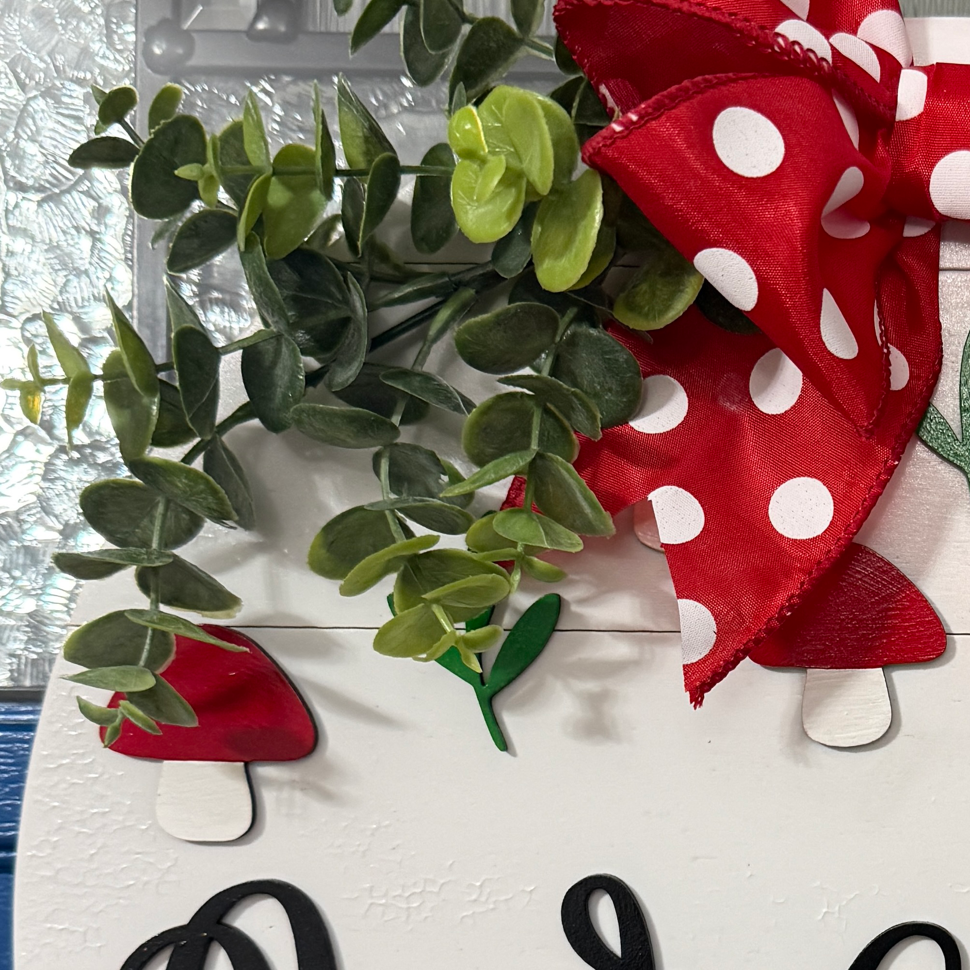 Cottagecore mushroom front door décor with greenery and red bow