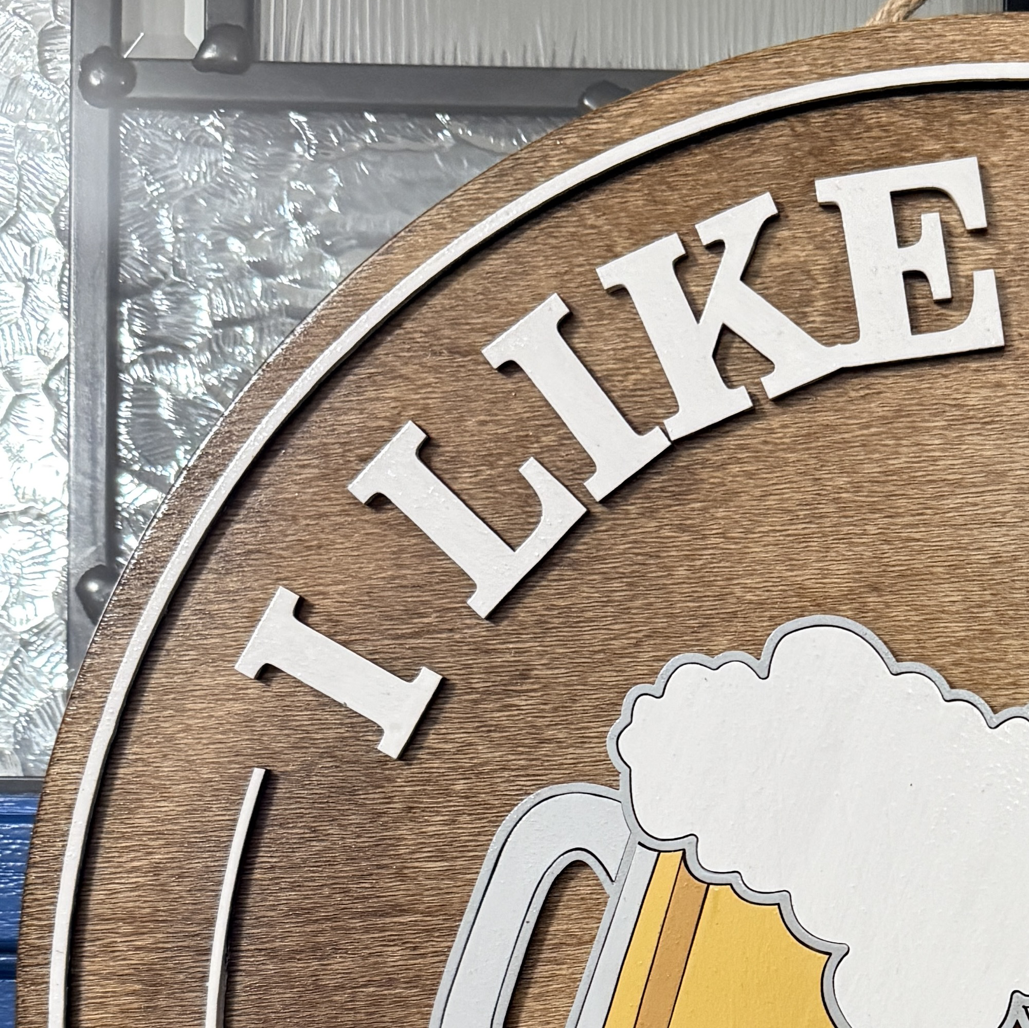 Close-up of top lettering “I like beer” on stained wood background with raised white text