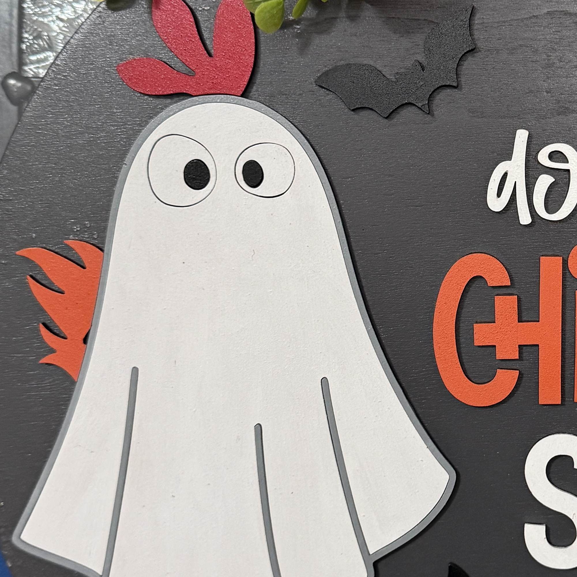 Close-up of ghost chicken character, candy corn, and jack-o’-lantern accents on the Halloween door hanger