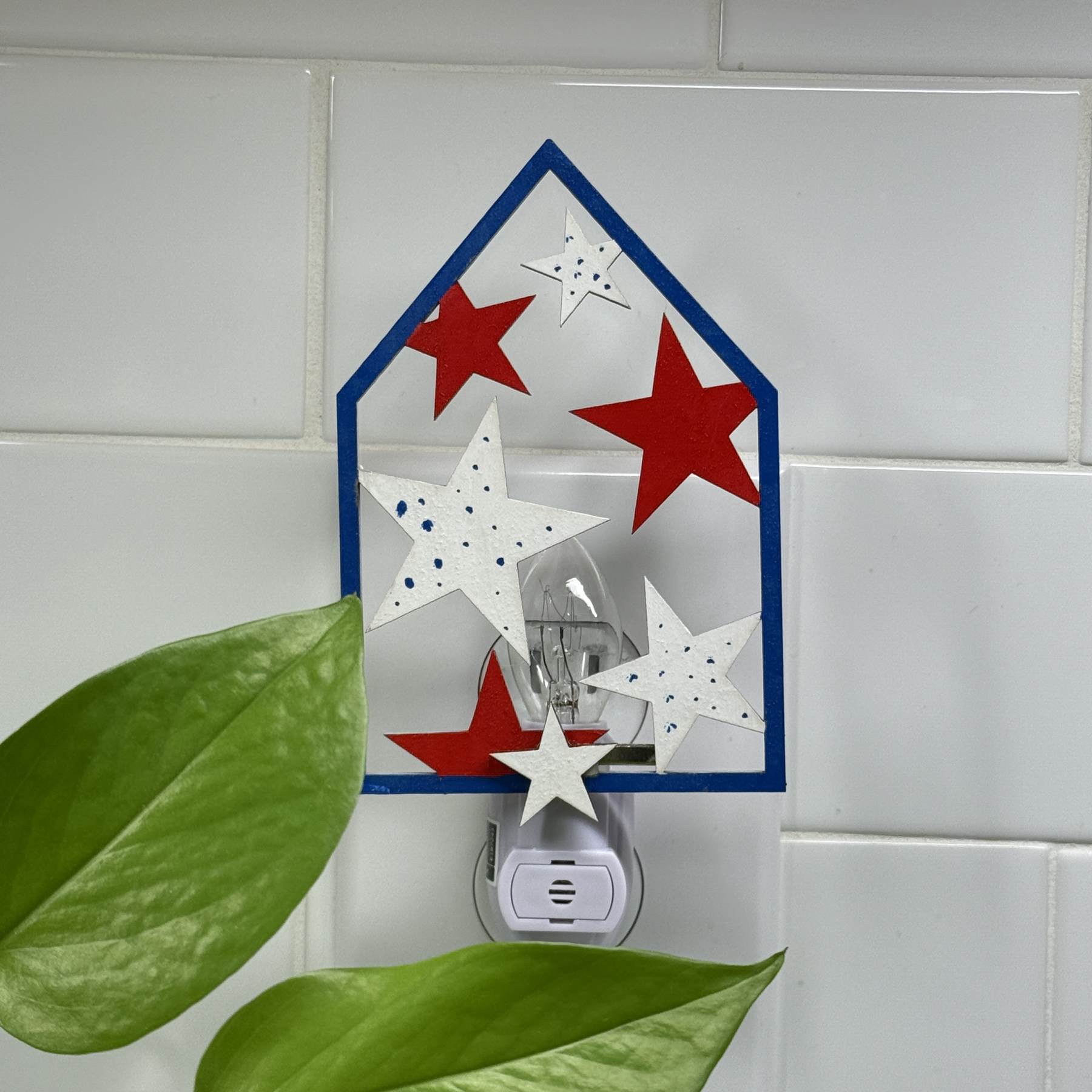 Blue wooden house-shaped night light with scattered red and white stars
