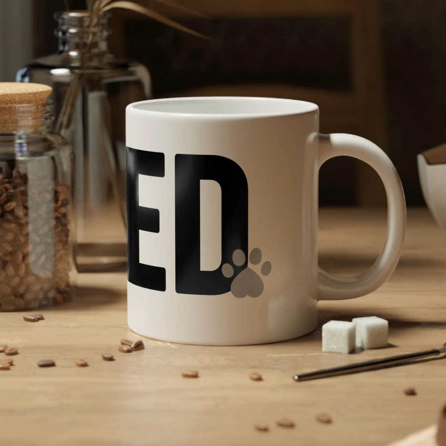 White ceramic dog lover mug with bold LOVED text styled on a cozy kitchen table with coffee beans and spoon