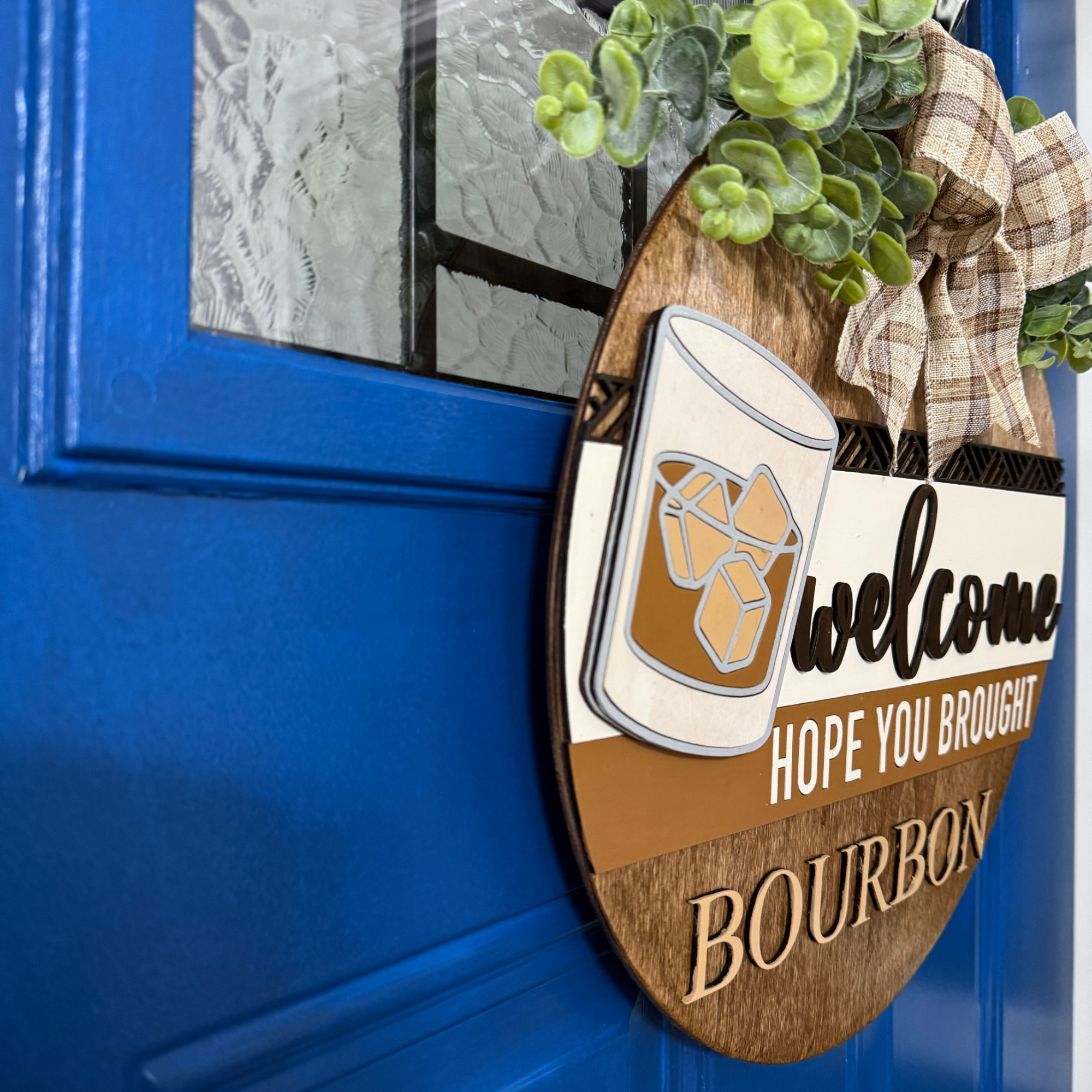 Angled side view of bourbon-themed door hanger showing layered wood construction on blue door