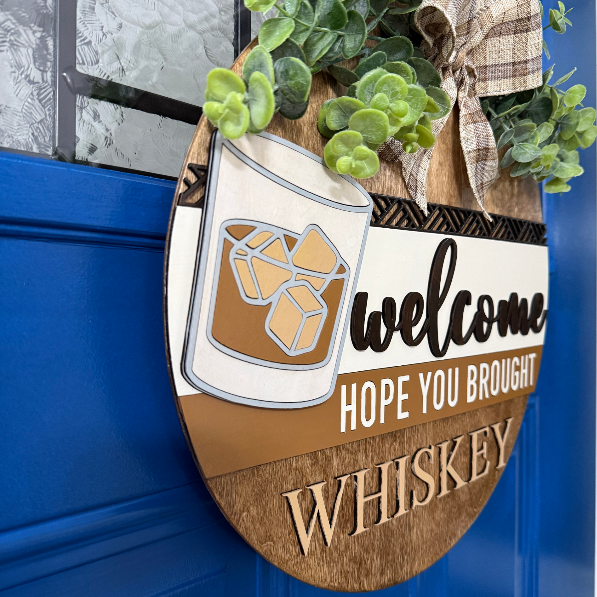 Angled side view of whiskey-themed door hanger showing layered wood construction on blue door