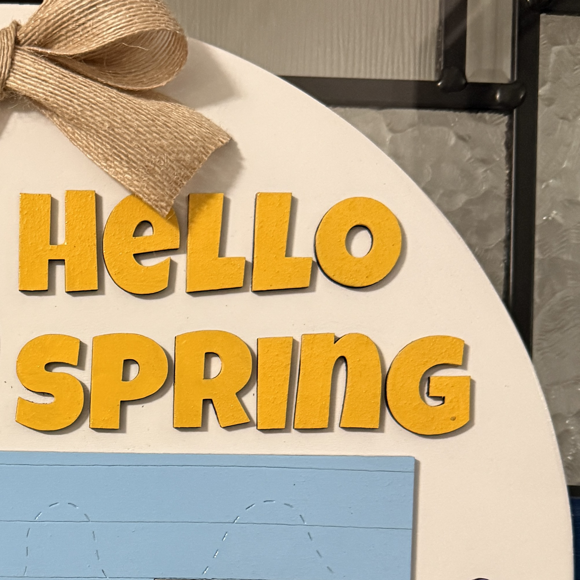 Close-up of “Hello Spring” text in yellow lettering on white background