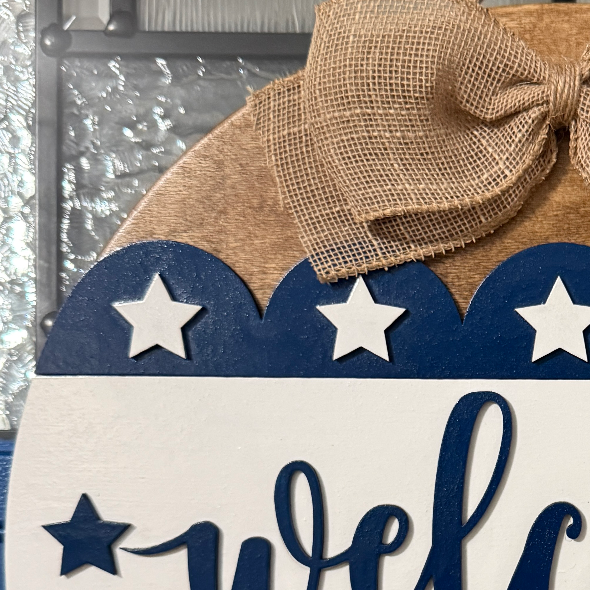 Close-up of navy blue star border and natural faux linen bow on the patriotic door hanger.