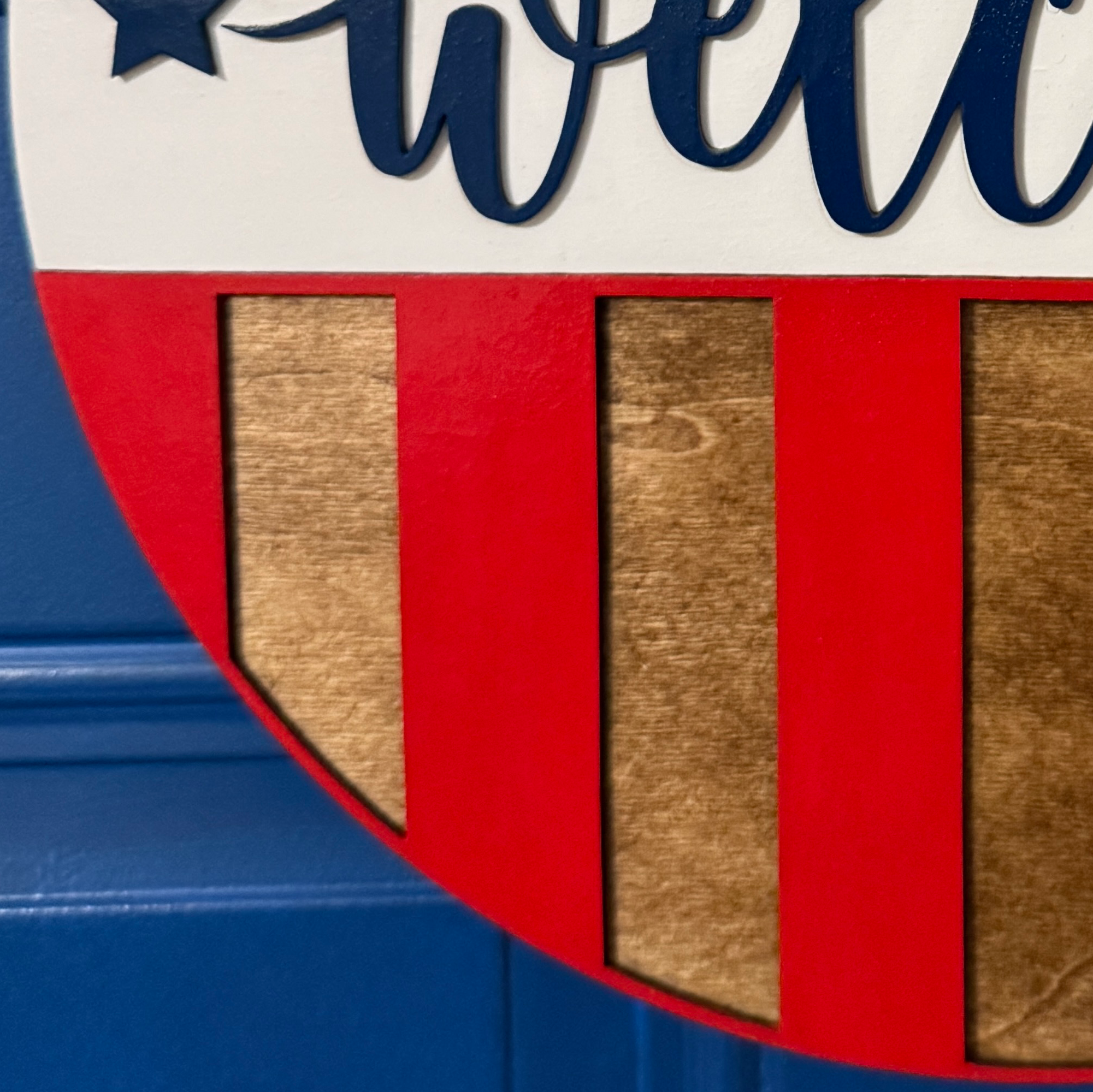 Detail of raised welcome lettering over red, white, and stained wood striped design.