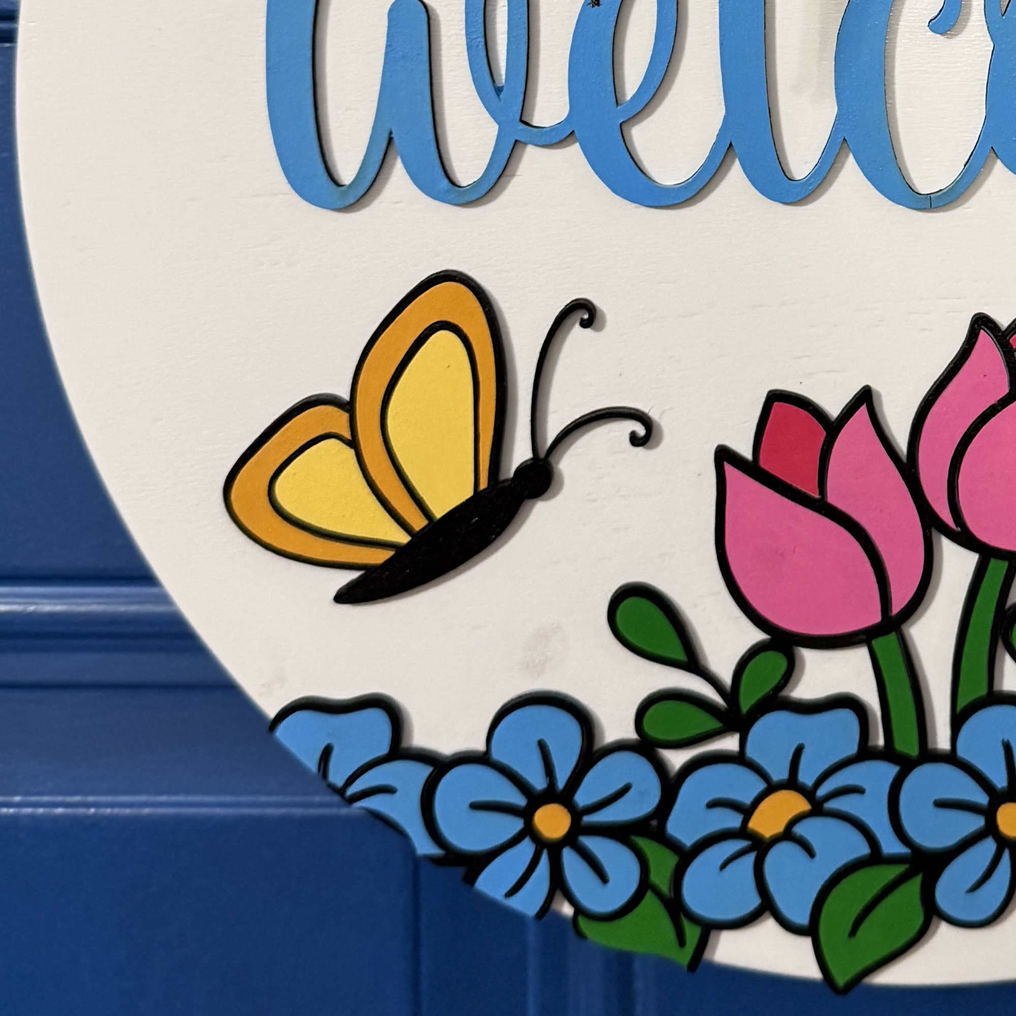 Close-up of yellow butterfly and pink tulips above blue flowers on hand-painted spring door hanger