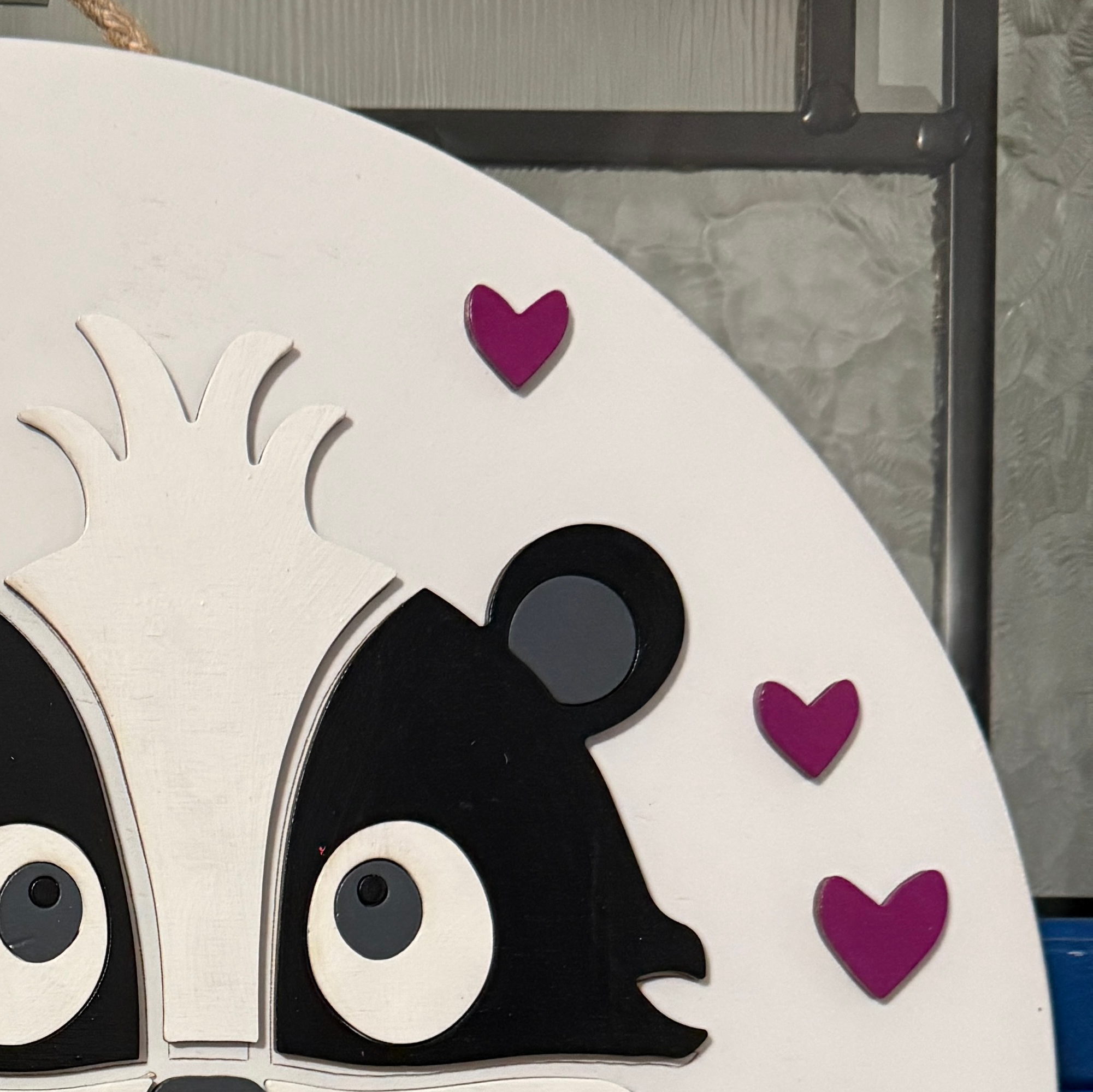 Close-up of layered black and white skunk face with pink cheeks surrounded by Valentine hearts