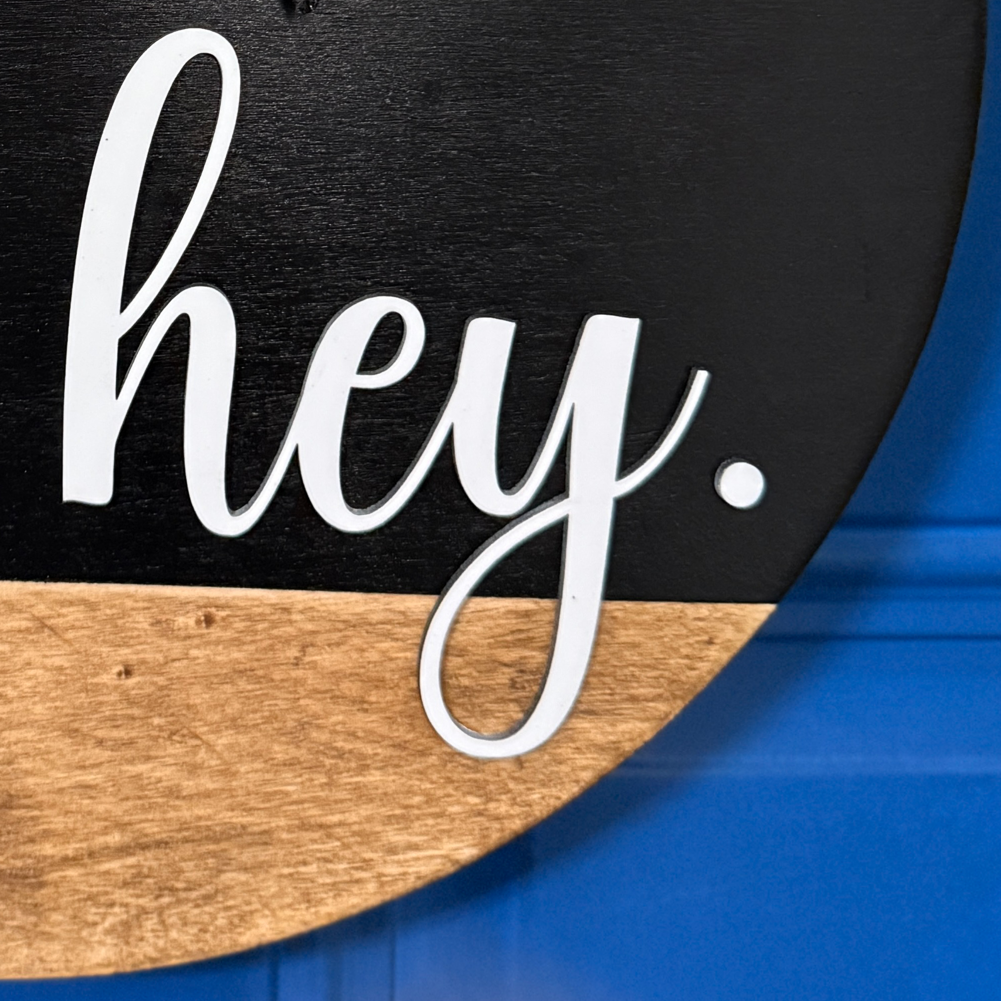 Close-up of white oh hey lettering on black painted wood door hanger with natural stained wood accent