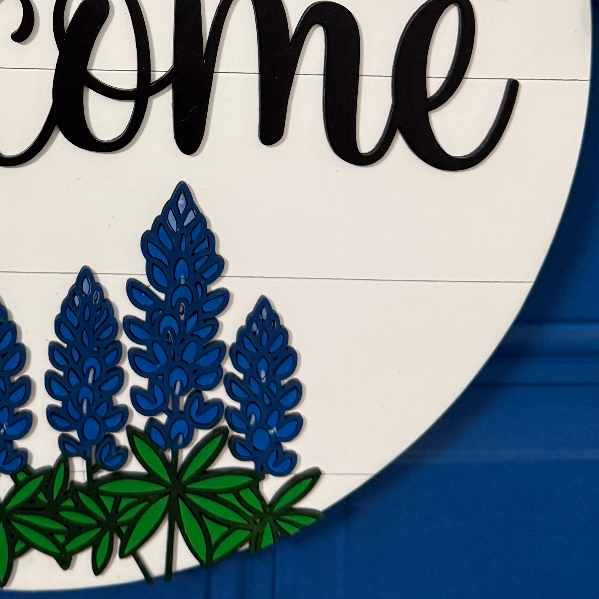 Layered bluebonnet floral detail on round wood door hanger